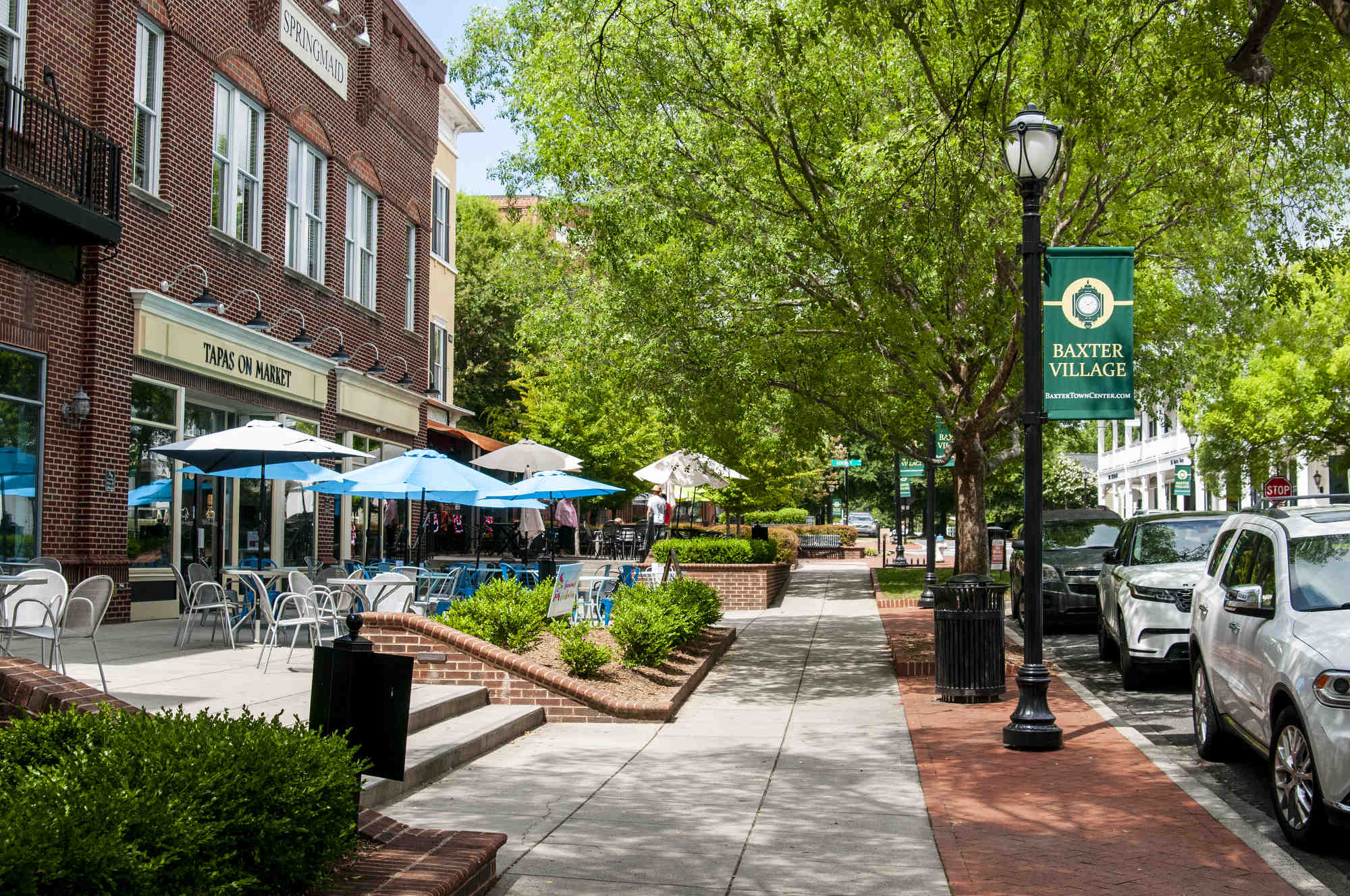 Tree-lined Baxter Town Center walkway with banners and outdoor seating.