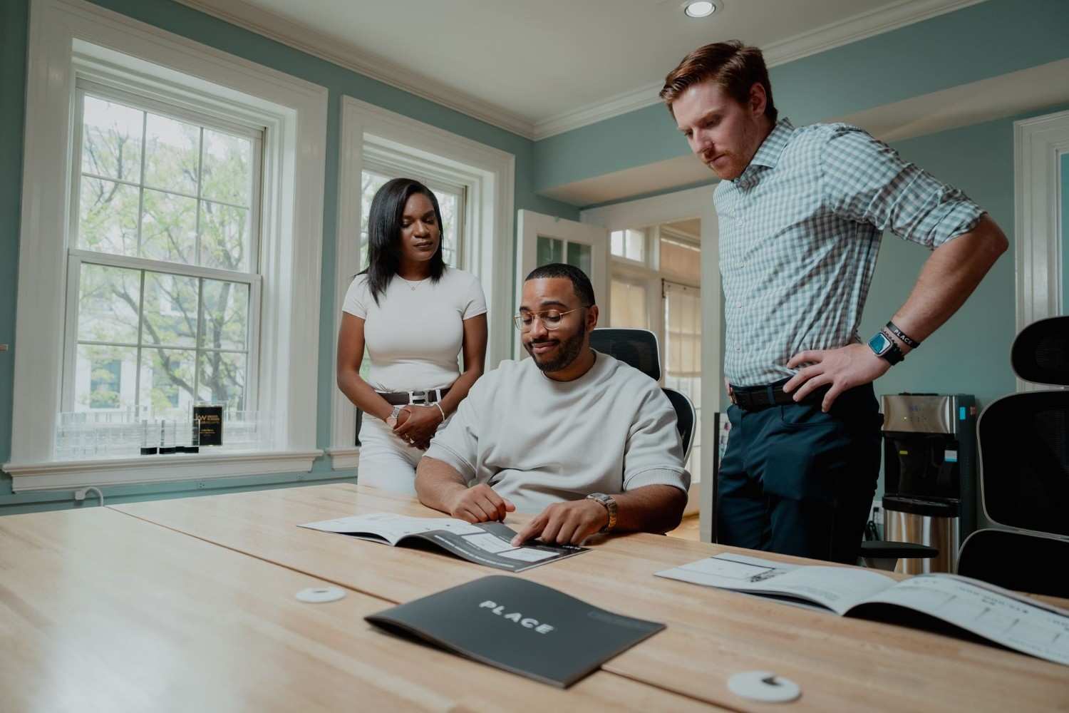 Three real estate agents collaborating and reviewing documents around a table in a modern office.