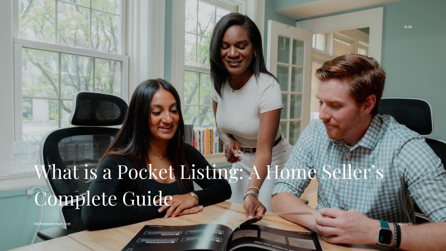 A real estate blog header image utilizing a full-width photo background with a subtle dark overlay. The scene features three people interacting around a light wooden conference table. An East Asian woman in a black top sits on the left, looking down at an open booklet with a smile. A Black woman in a white t-shirt stands behind her, leaning forward to point at the pages, while a white man with red hair and a green plaid shirt sits on the right, attentively reviewing the booklet. Bold white text across the bottom reads, 