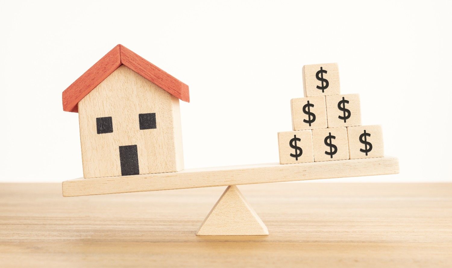 Image of a wooden house, and wooden blocks with a money symbol, symbolising balancing the value of the home