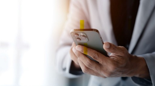 A man in formal attire holding a smartphone.