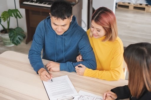 A couple engaged in signing a contract at a table, highlighting their commitment to an agreement.