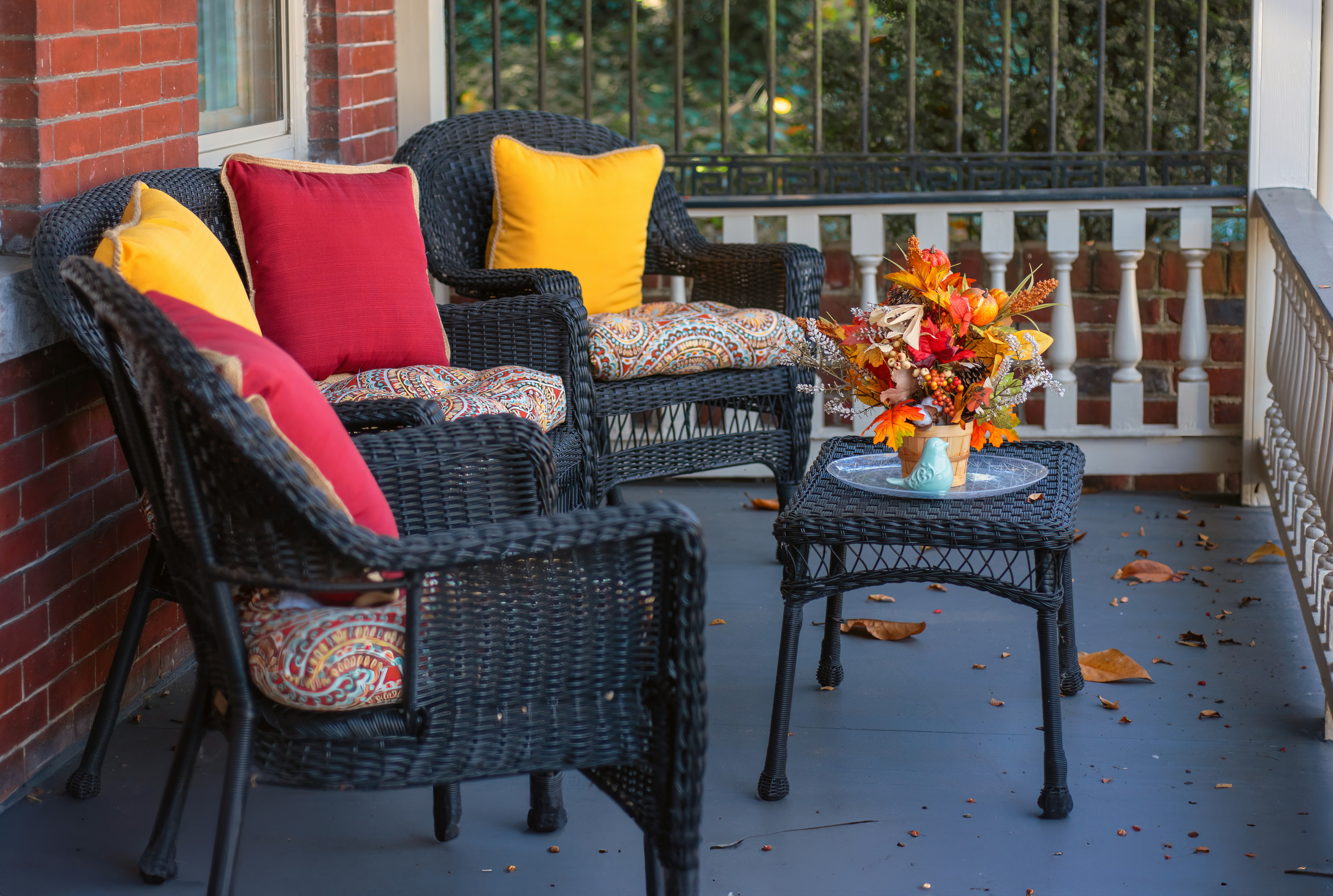 Front porch in Amarillo decorated for fall with wicker chairs, colorful pillows, and a seasonal floral arrangement, highlighting cozy curb appeal during the autumn real estate season