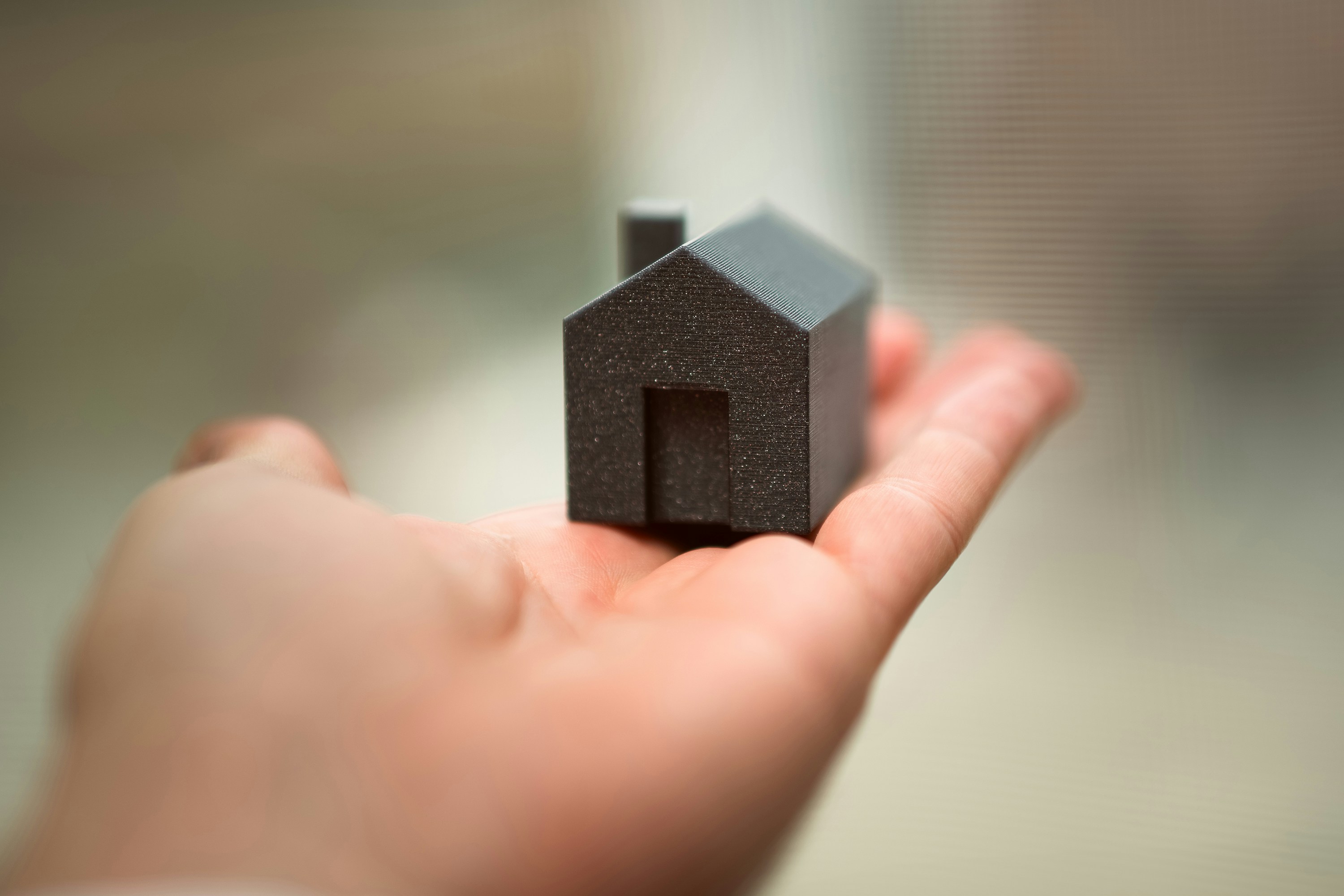 Close-up of a hand holding a small house model, symbolizing first-time home buying in Amarillo, Texas