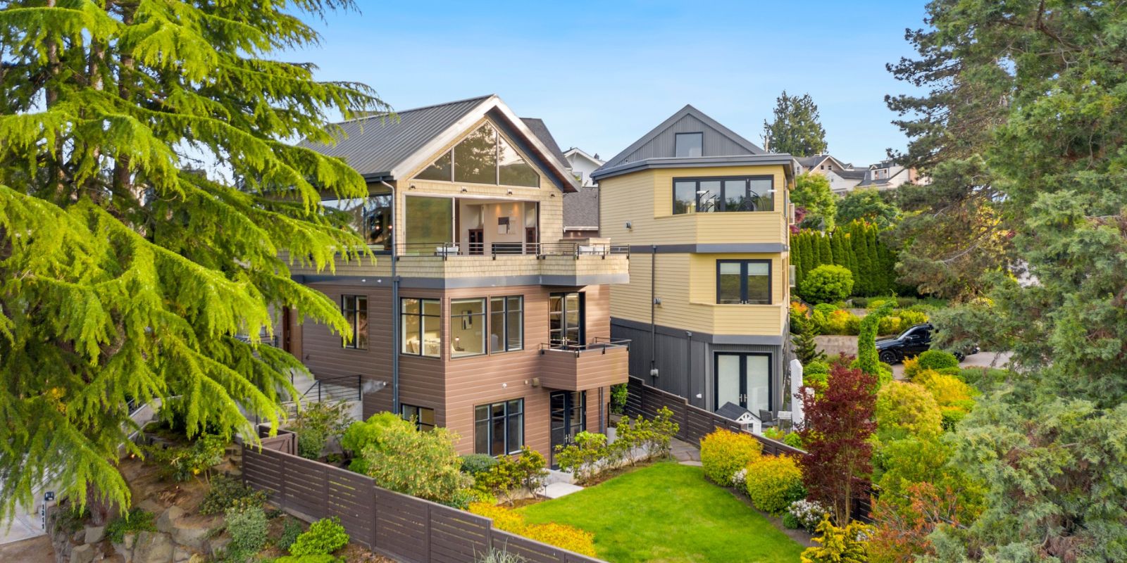 Charming craftsman-style home in West Seattle with a manicured front yard, covered porch, and lush greenery under a clear blue sky.