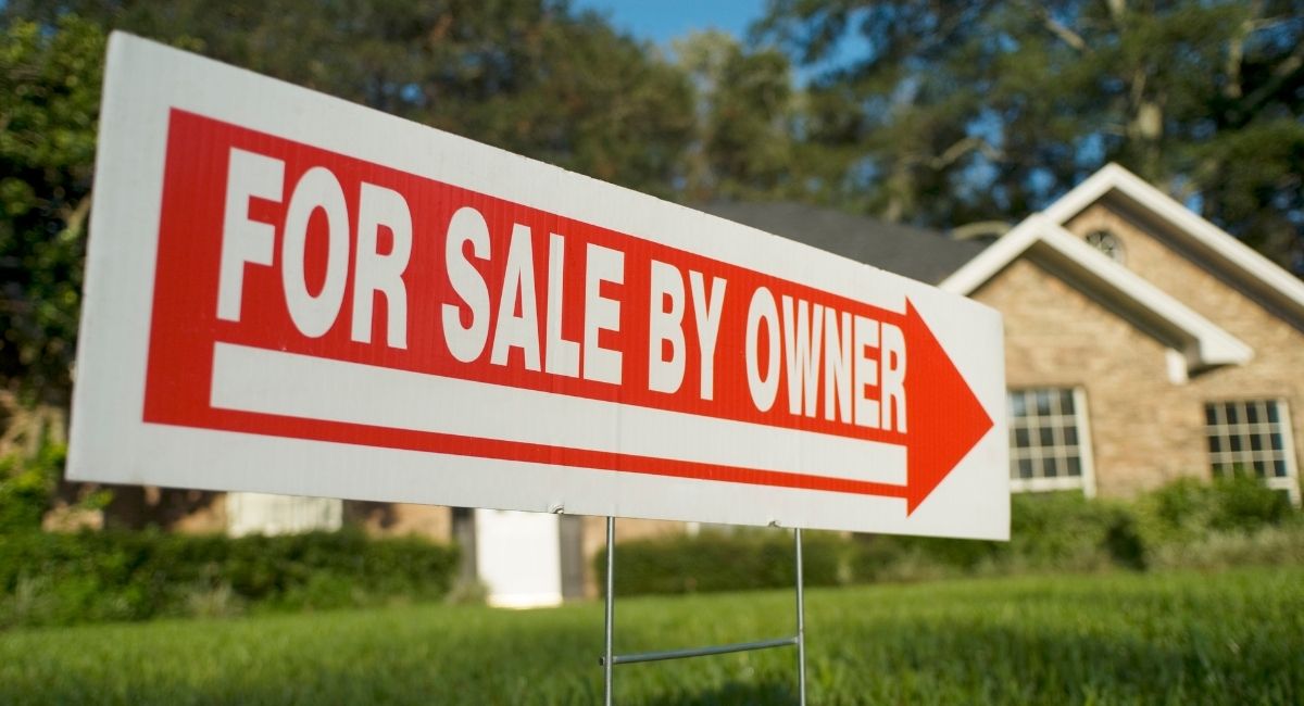 For Sale By Owner yard sign displayed in front of a residential property.
