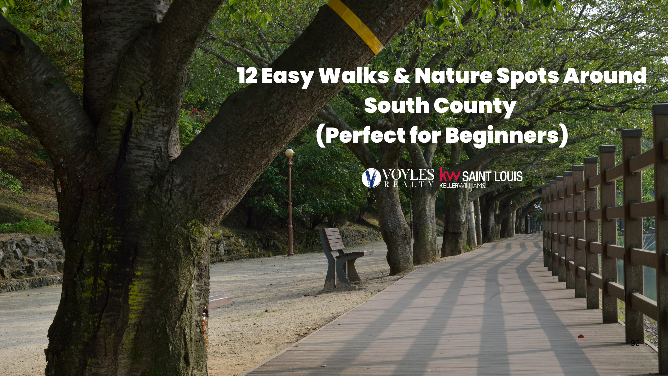 Shaded wooden boardwalk trail lined with large green trees, park benches, and a wooden fence, featuring text overlaying the image that reads 