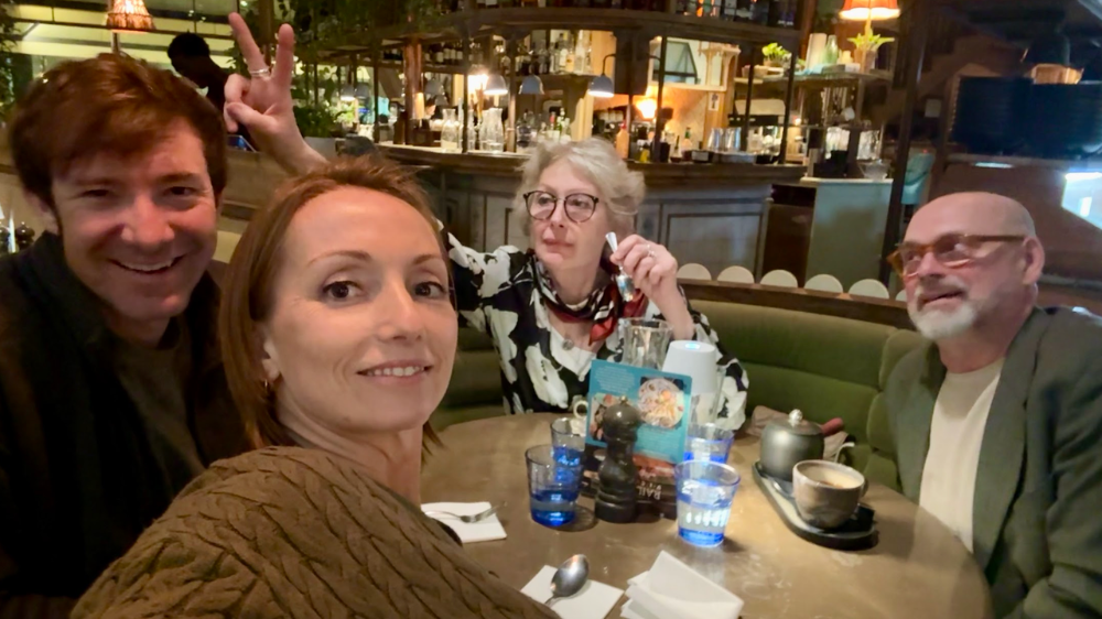 Two couples are sat around a table in a restaurant posing for a photo