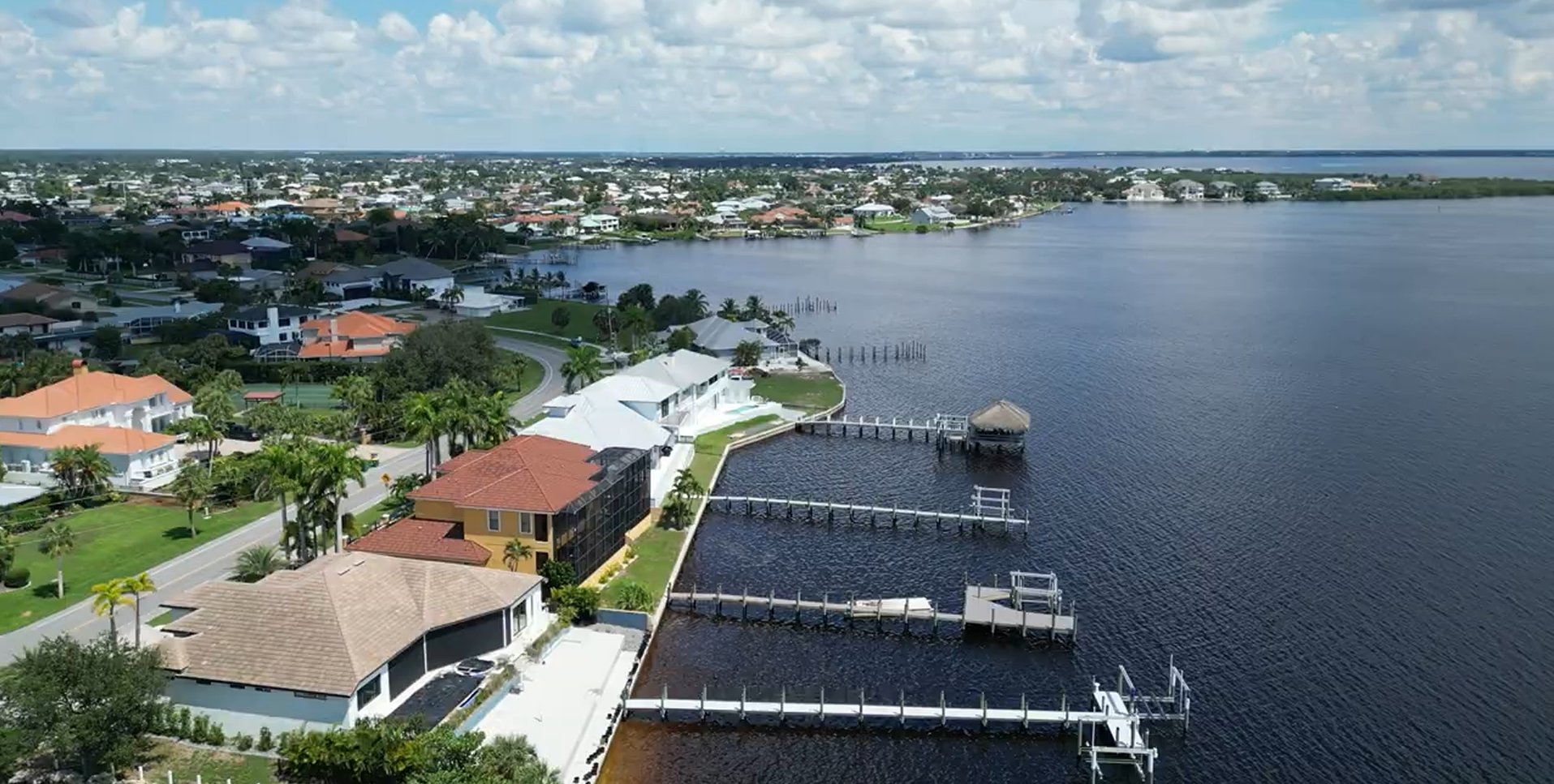 Gorgeous waterfront home in Punta Gorda Isles, Florida, with private dock, boat, lush landscaping, and Charlotte Harbor at sunset. 