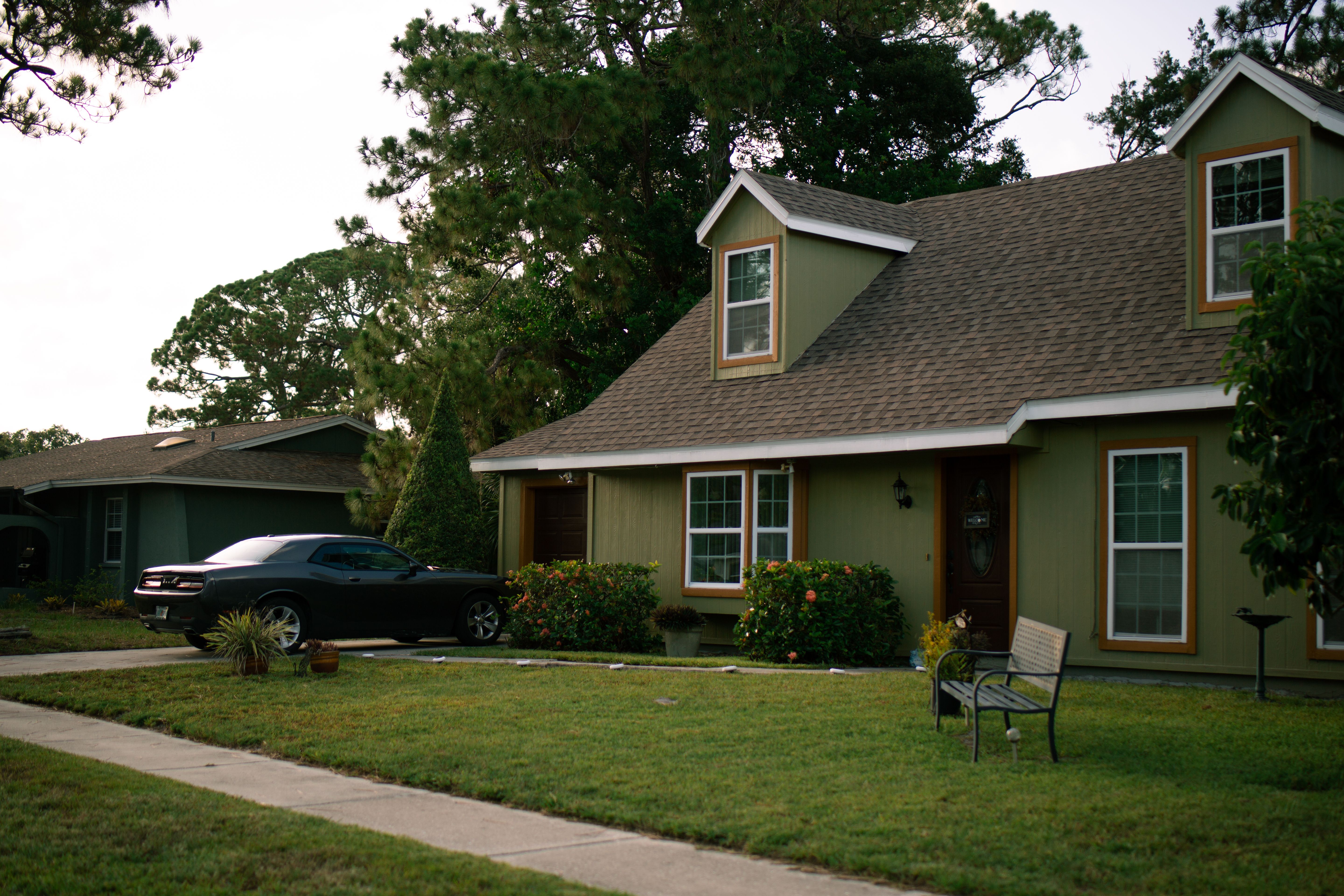 Affordable single-family home for sale in Lehigh Acres, Florida, with a large yard, palm trees, and bright sunshine.