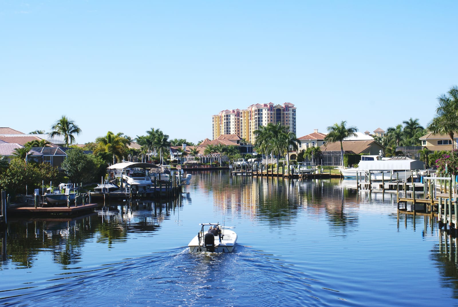 Beautiful residential neighborhood in Cape Coral, FL with palm trees, well-maintained homes, and a canal, perfect for Florida real estate.