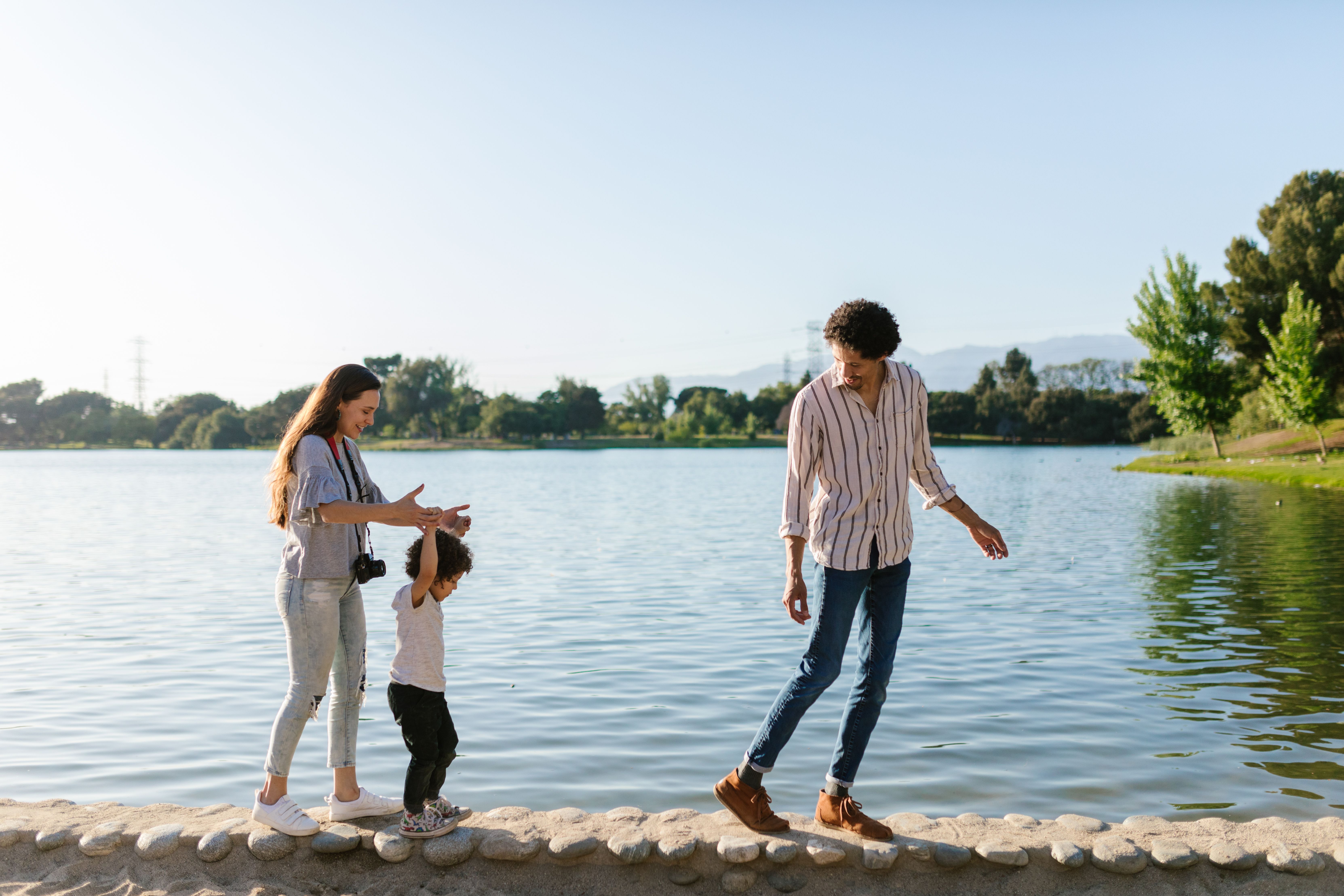 Happy family enjoying Babcock Ranch, Florida lifestyle, walking by lake with Founder’s Square in background. Southwest Florida real estate.