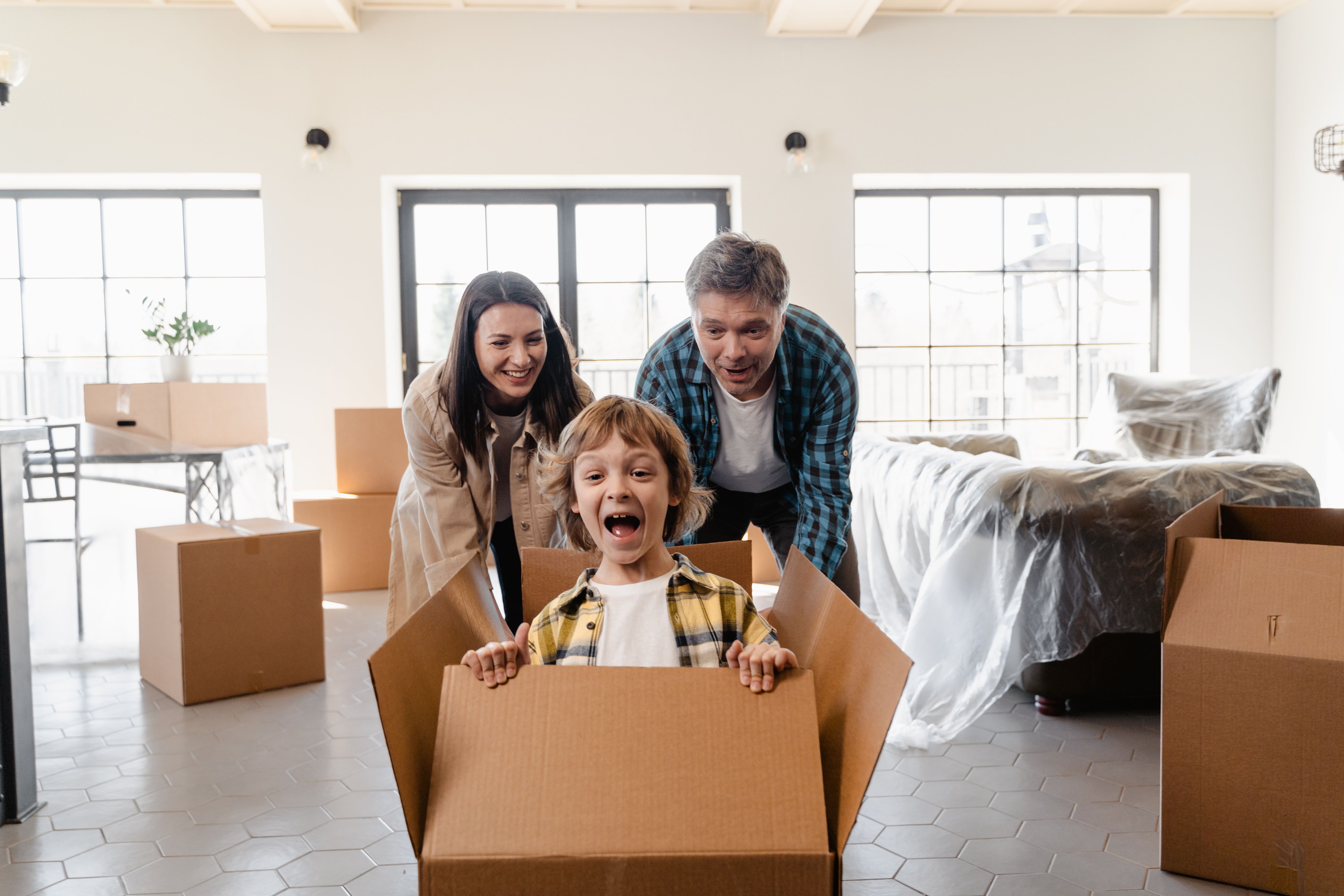 Family unloading moving truck in front of a new spacious home with palm trees in Lehigh Acres, Florida. Excitement for moving to Southwest Florida