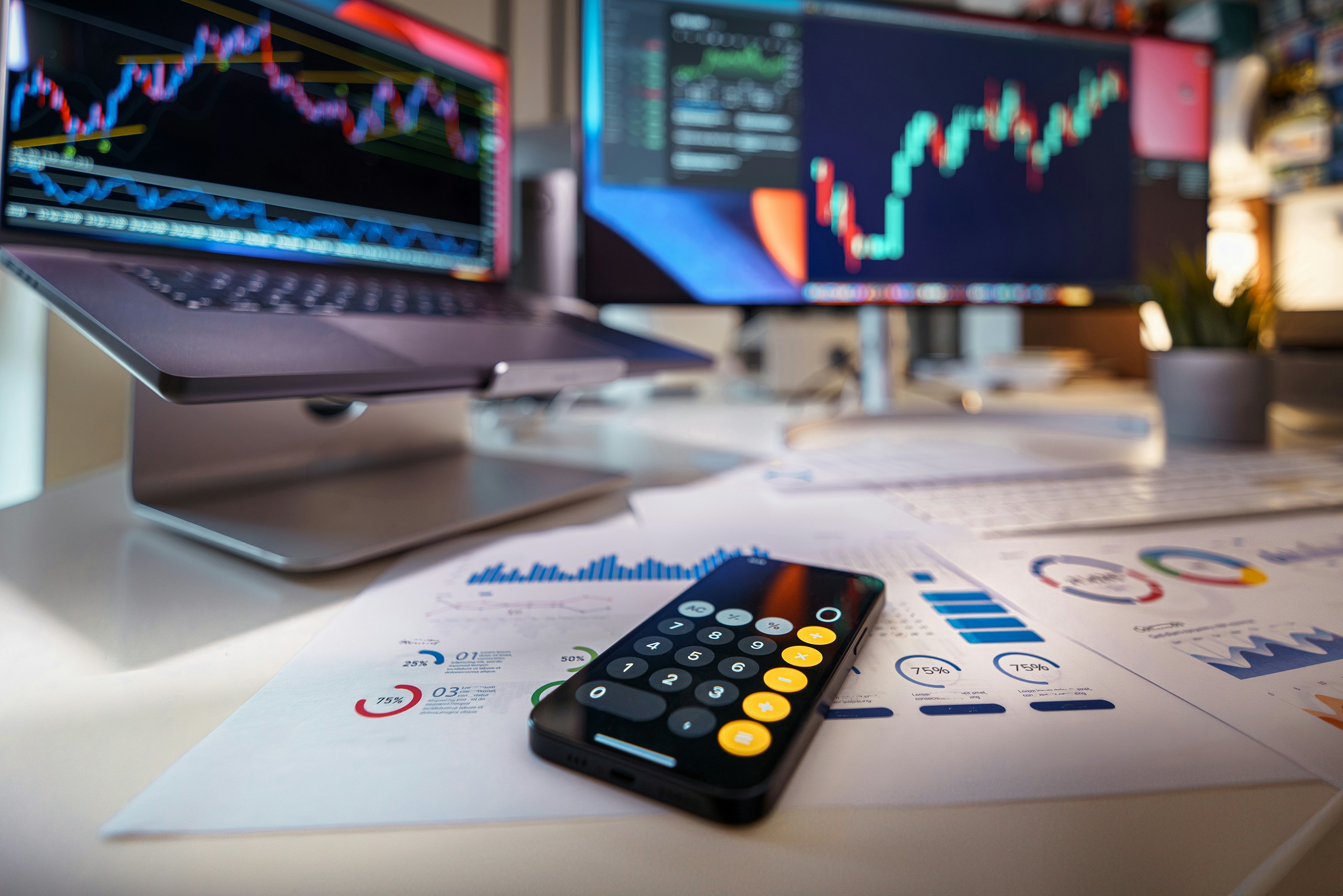 Digital calculator and financial charts on desk with real estate market trends displayed on monitors, representing strategic home pricing analysis in Birmingham and Tuscaloosa 2025