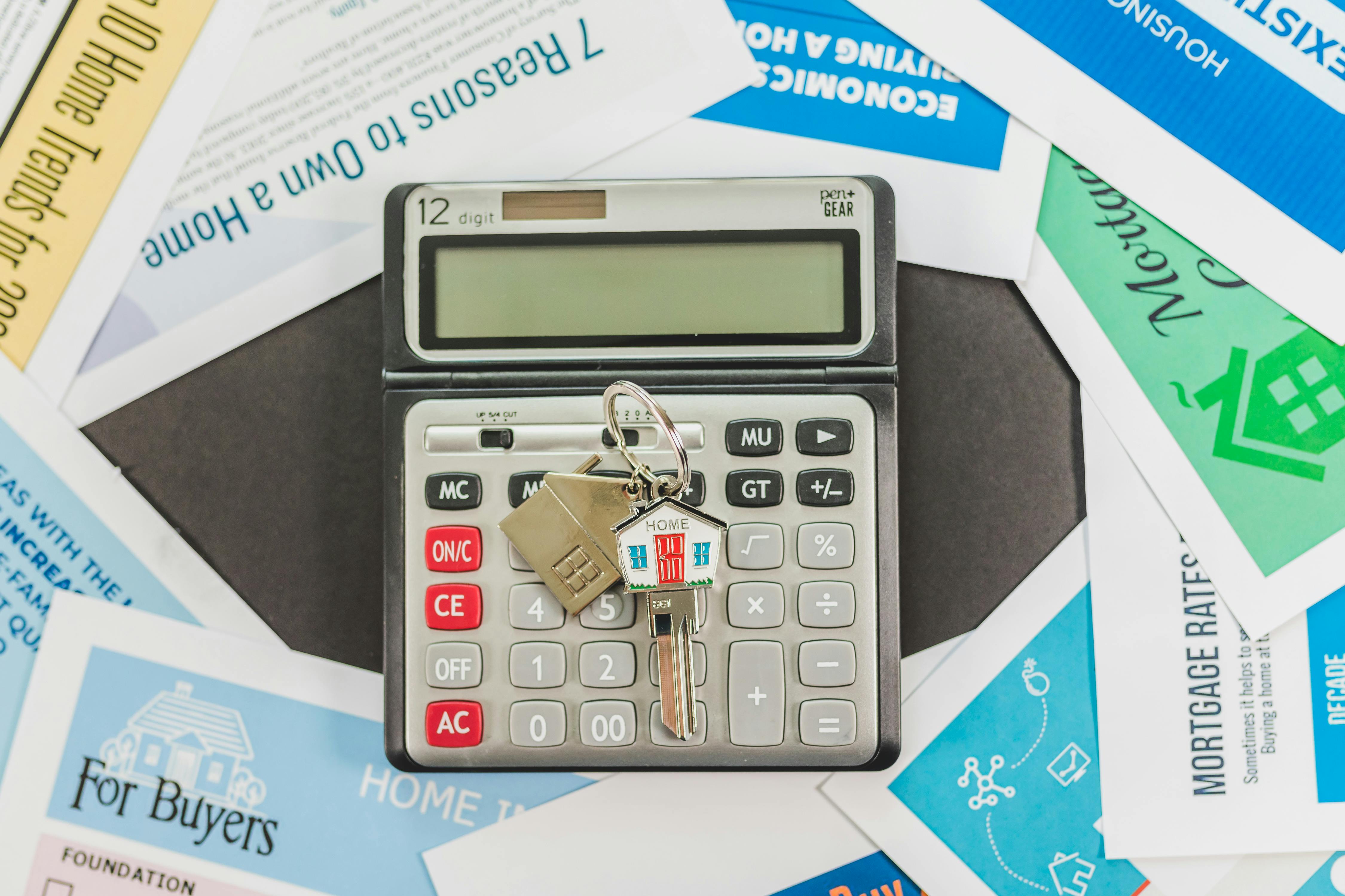 House key with home-shaped keychain on top of calculator and real estate documents, representing the home selling process after accepting an offer in Alabama