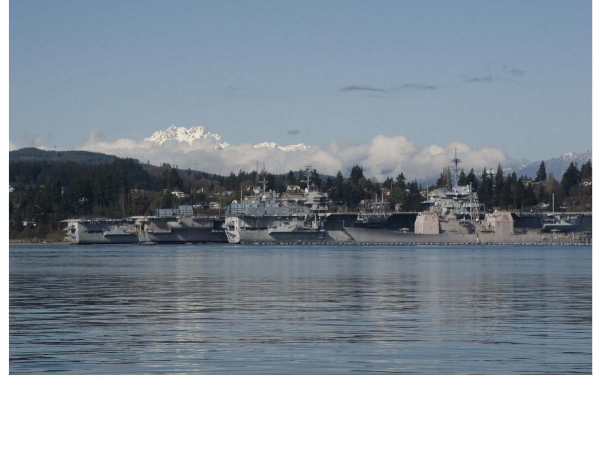 naval base kitsap with docked warship and olympic mountains in the background