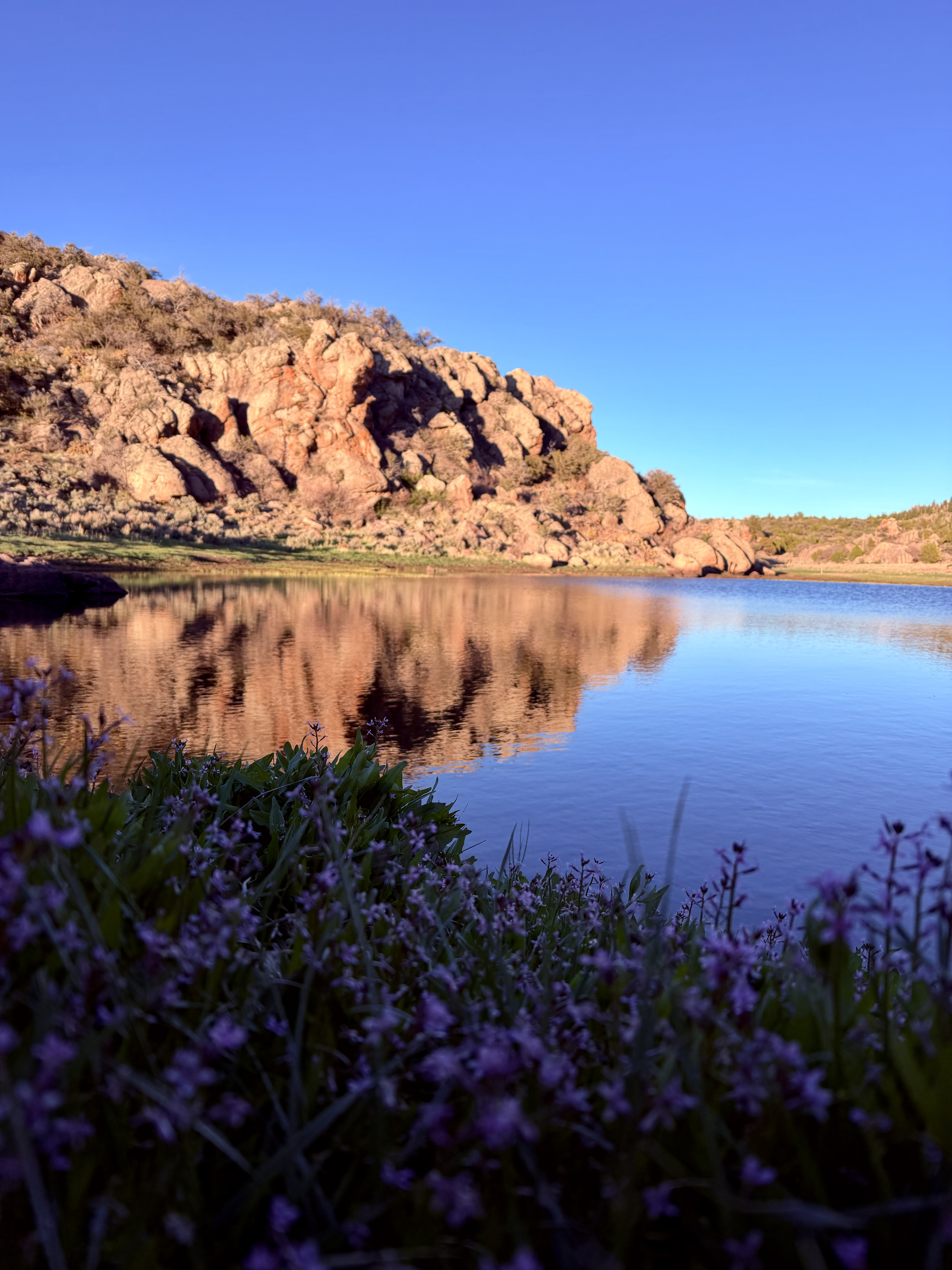 Mountain reservoir reflecting red rock cliffs during sunset in Southern Utah