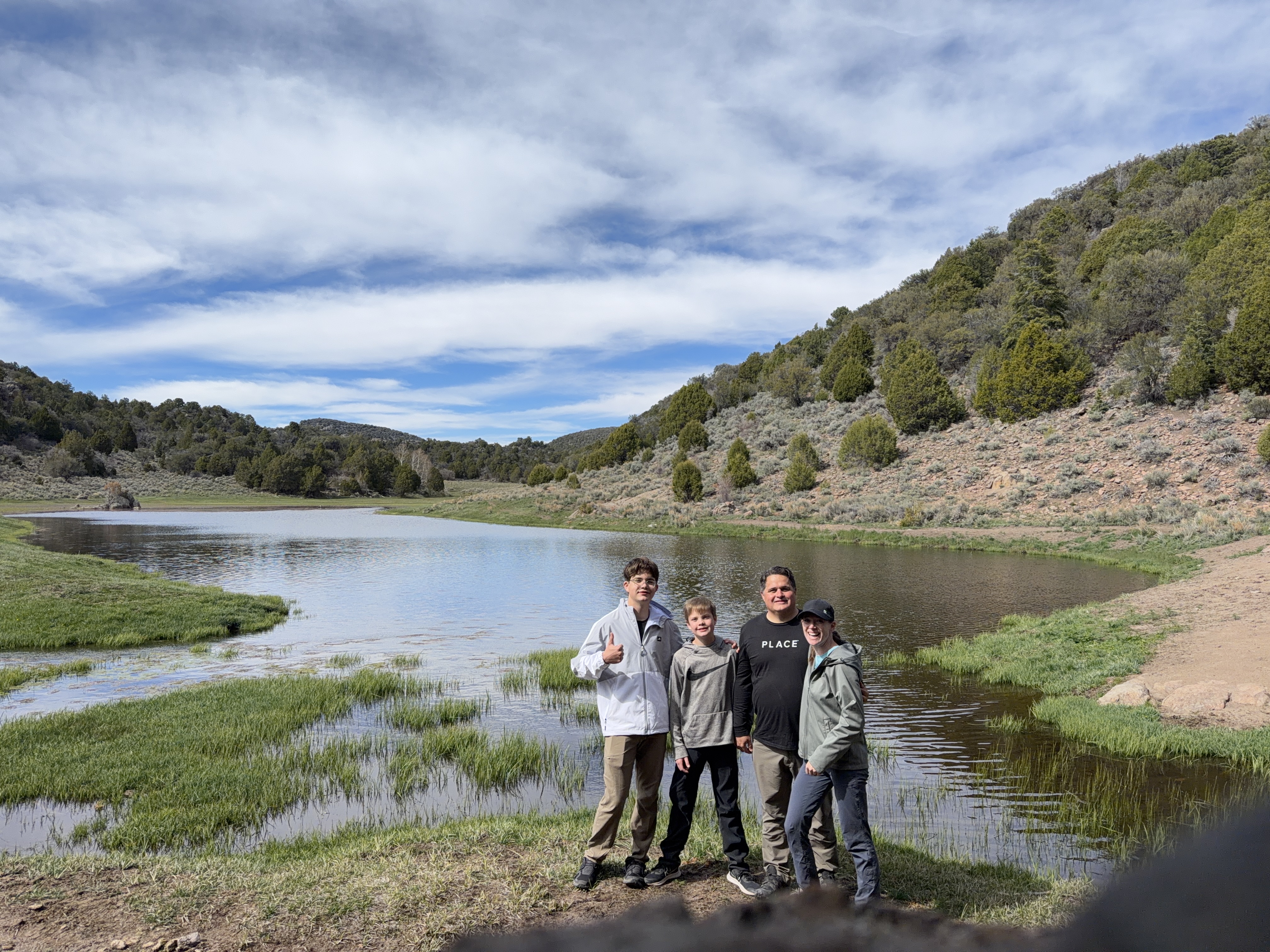 Family standing beside a mountain reservoir during a backpacking trip in Southern Utah