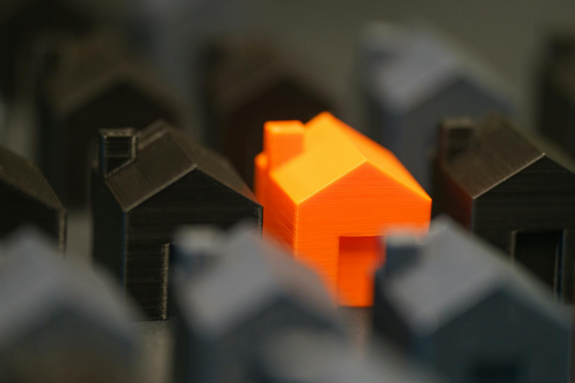 Photo by Jakub Zerdzicki: https://www.pexels.com/photo/striking-orange-model-house-amidst-black-miniatures-33305157/
