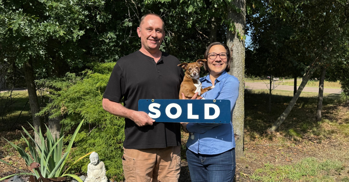 Home sellers holding a SOLD sign and their dog in the yard after an off-market home sale in Chippewa Falls, Wisconsin