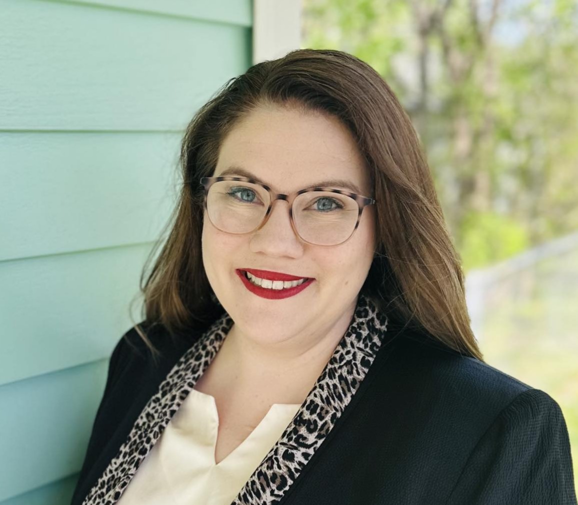 white woman with red lipstick and brown hair in a black blazer
