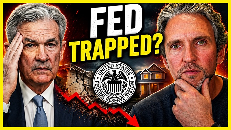 Federal Reserve Chair Jerome Powell and Anton Stetner appear beside a Federal Reserve logo, a falling red market graph, and a house image under bold text reading “Fed Trapped?” symbolizing concerns about inflation, interest rates, and the housing market.