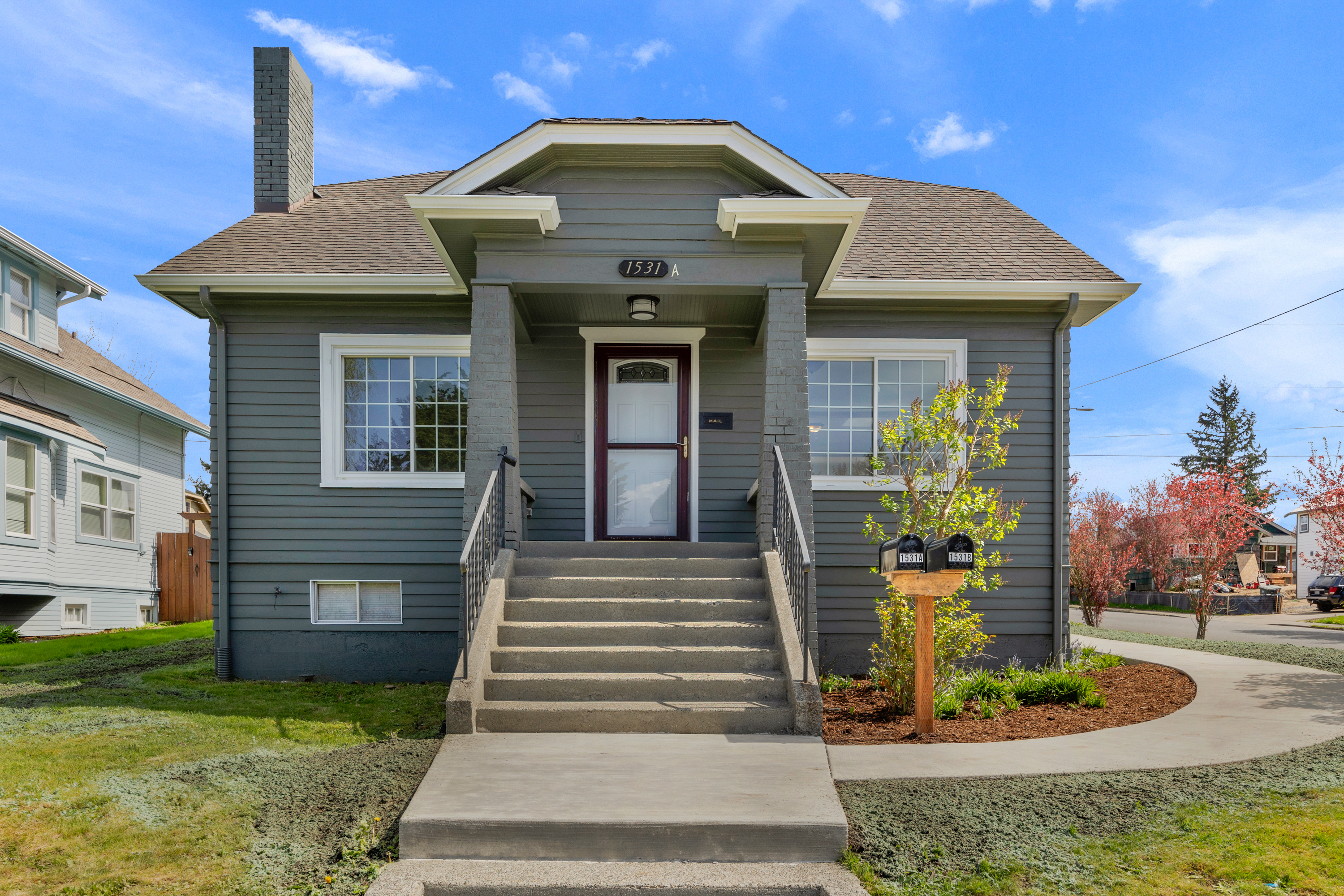 Exterior view of 1531 Virginia Ave Unit 1, a charming Craftsman-style condo in Everett, WA, showcasing its classic architecture and lush surroundings.