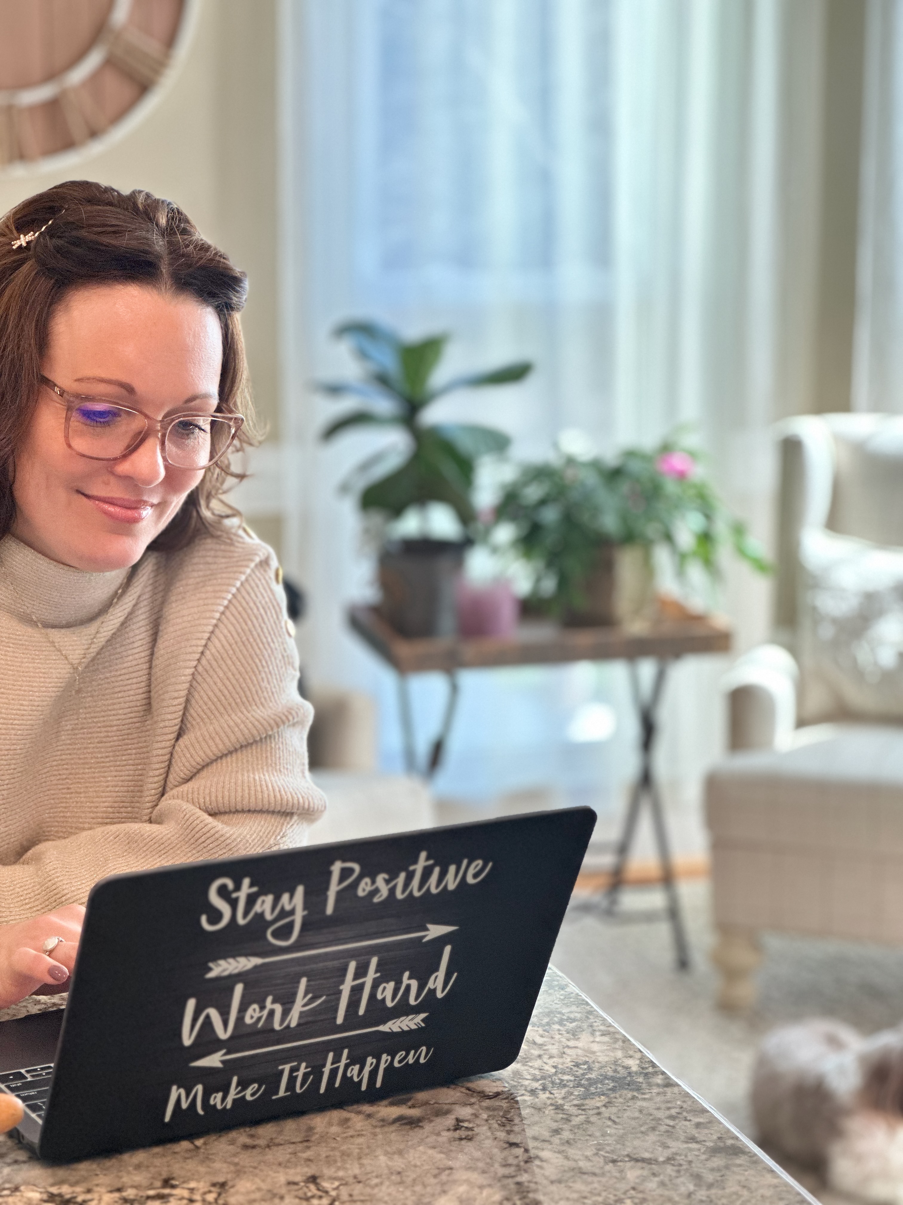 Crystal Rierson-Villeneuve writing at home in soft natural light with a laptop that reads ‘Stay Positive, Work Hard, Make It Happen,’ reflecting on Viktor Frankl’s Man’s Search for Meaning.
