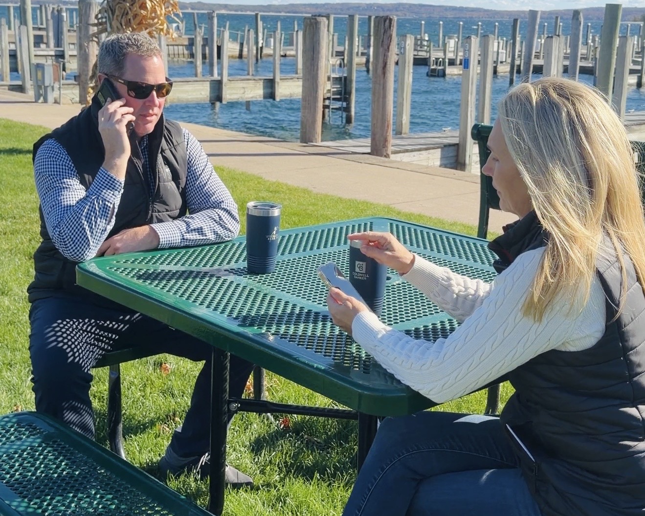 Bill and Alisa from the Winslow Group working outside by the water in Northern Michigan, symbolizing year-round real estate activity and spring market preparation.