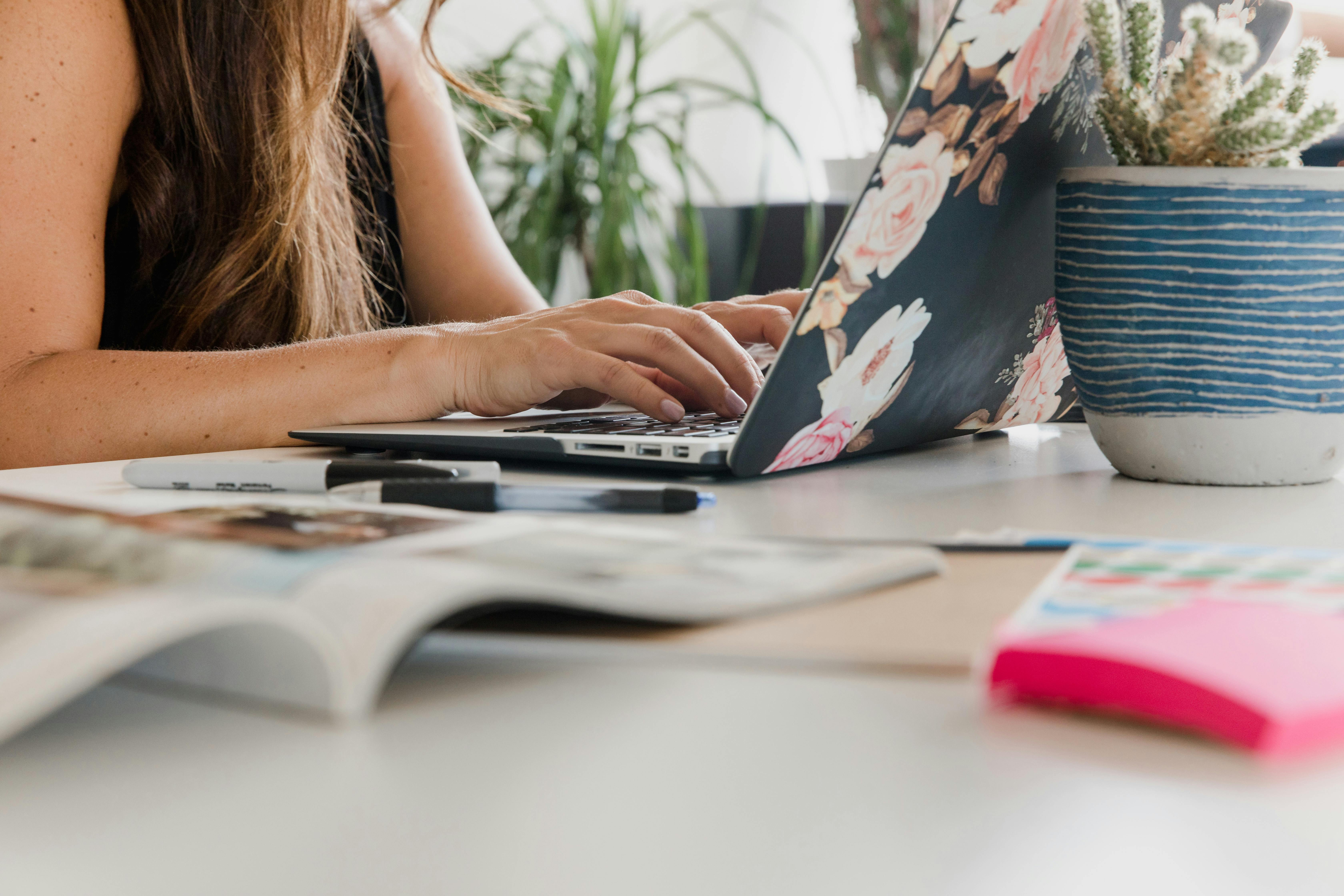 Real estate agent working remotely on a laptop with floral cover, planning marketing and business growth strategies at a boutique brokerage in Lockport, IL