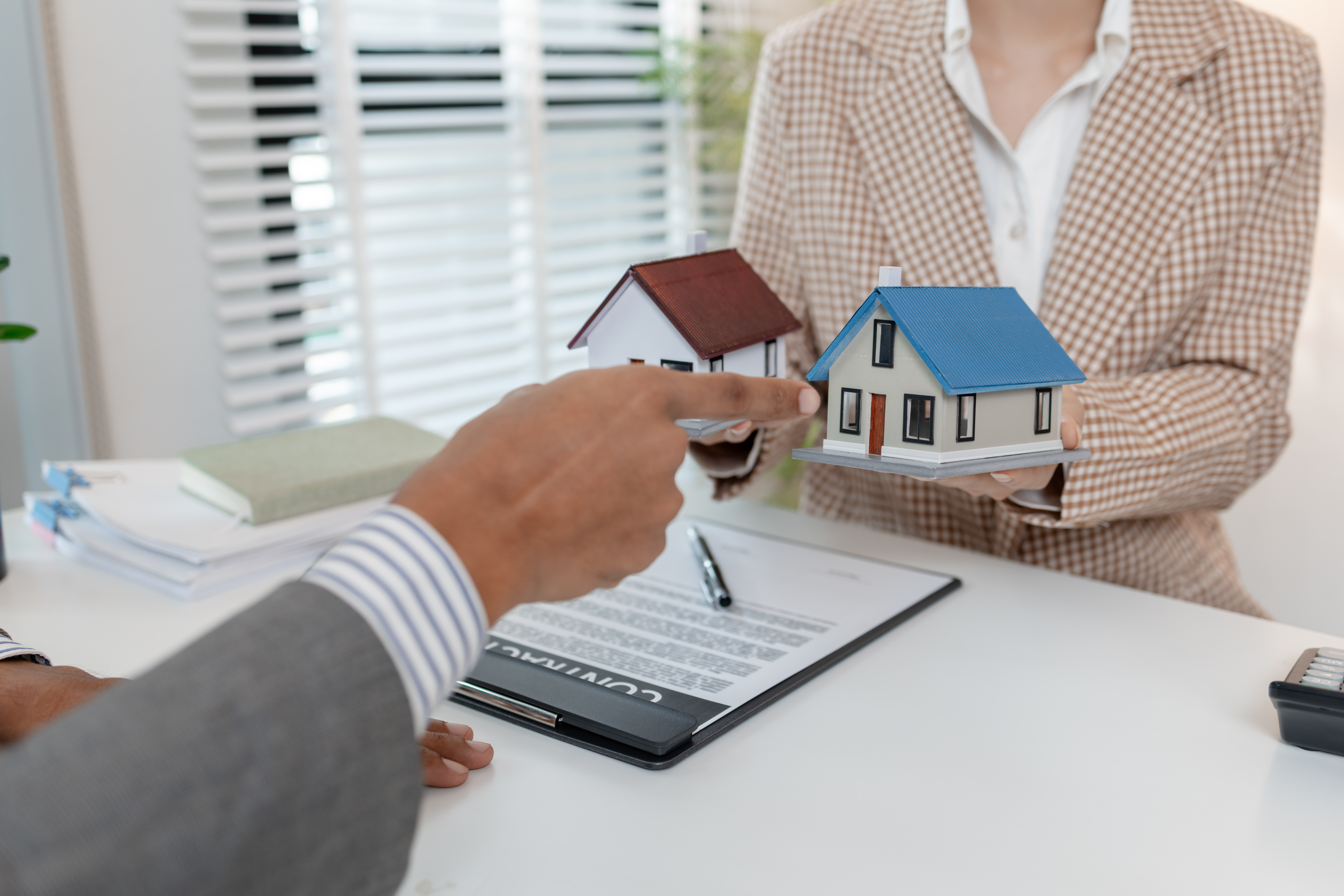 hand pointing at two small houses