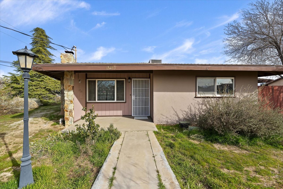 Front exterior view of single story home at 13285 Mesquite Road in Apple Valley CA showing the walkway to front door and surrounding yard under a clear sky