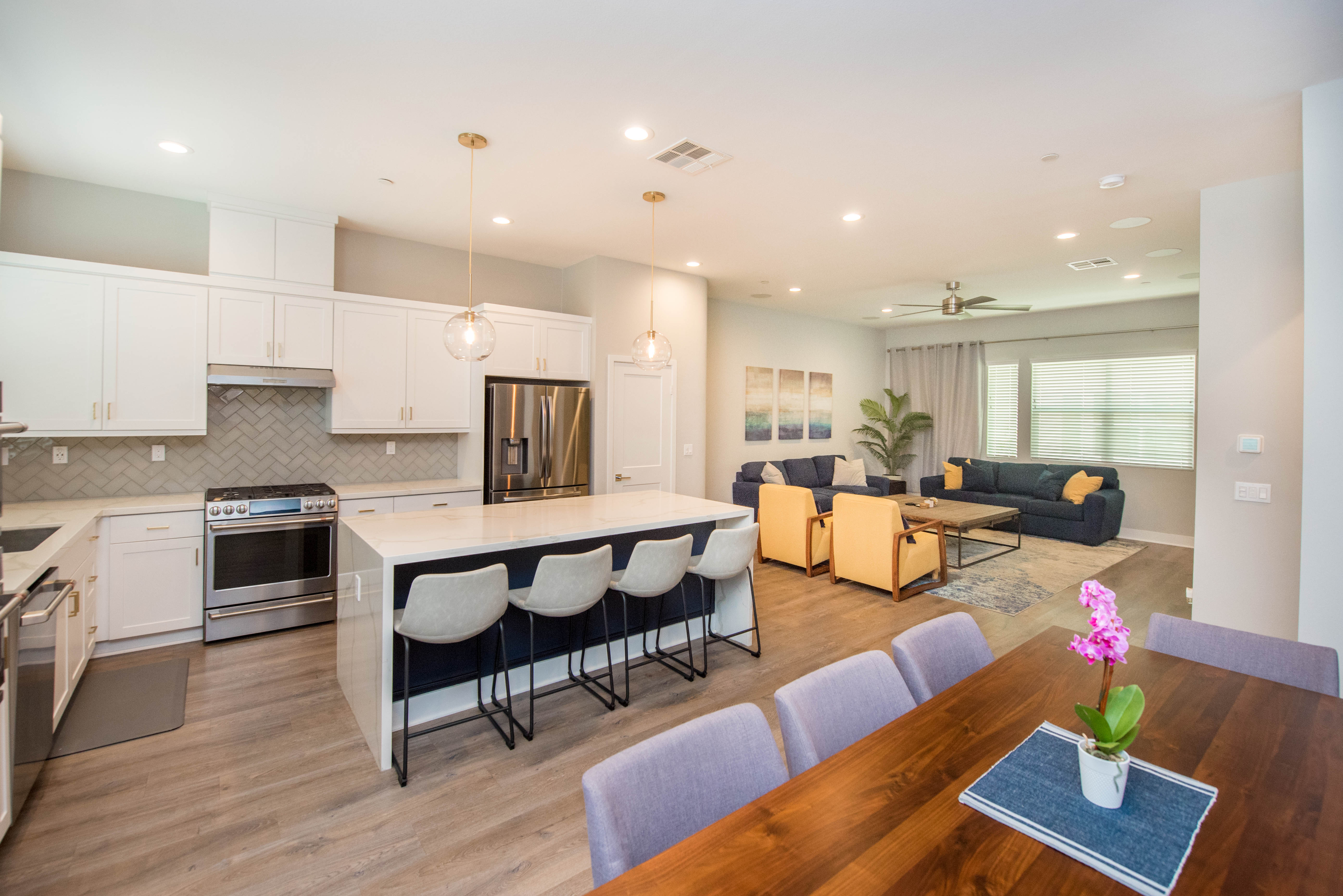 Open-concept kitchen, dining and living area at 983 E Mason Lane #123 in Anaheim, featuring a large waterfall-edge island, white cabinetry and spacious modern living areas.