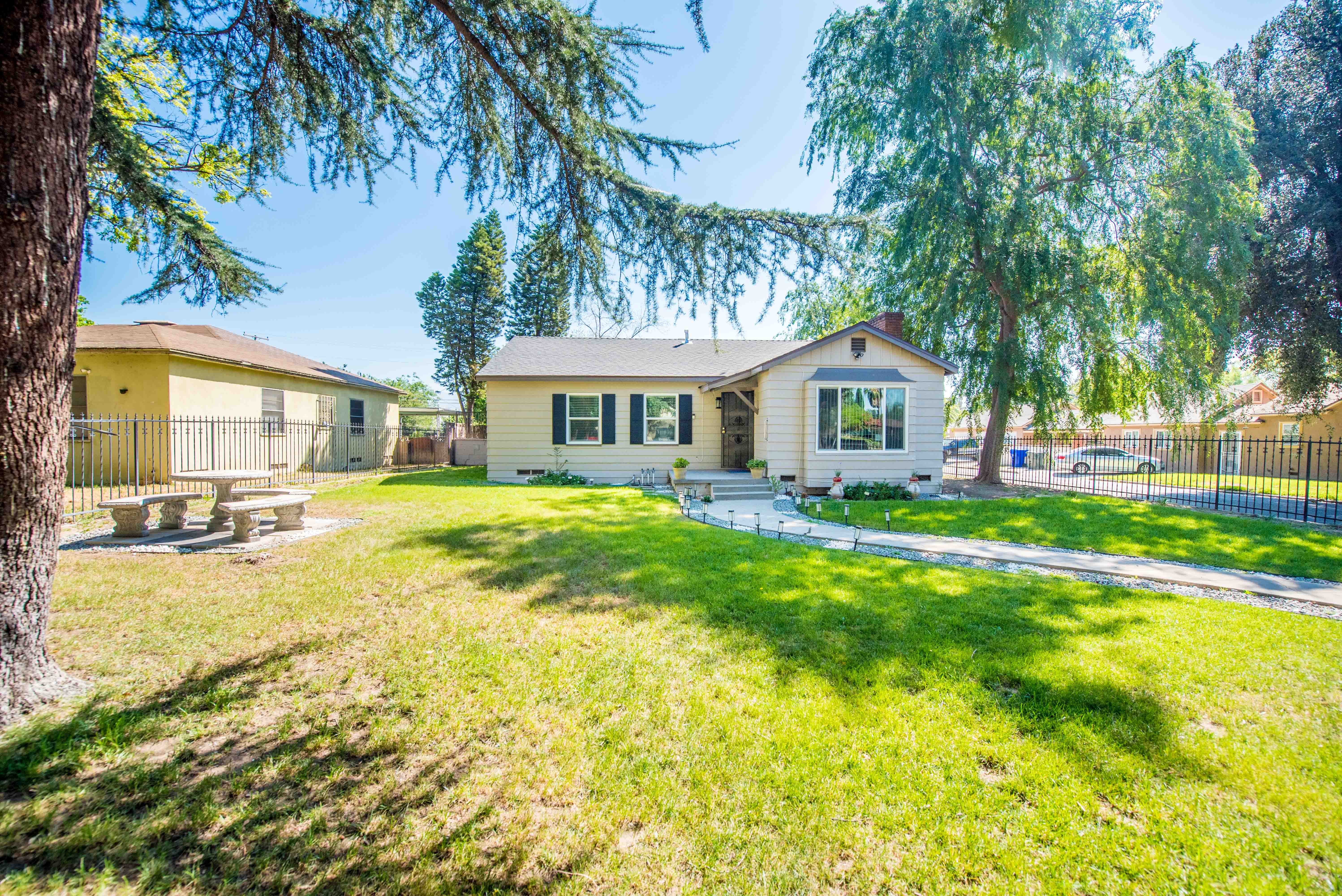 Front exterior of fully remodeled 3-bedroom home at 2803 Ladera Rd in North San Bernardino featuring landscaped yard, curved walkway, and mature trees.