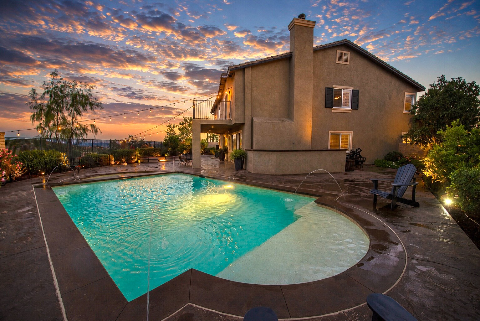 Backyard design at 35944 Wilcox Lane in Murrieta featuring a saltwater pool and spa, stamped concrete patio, outdoor gathering areas, and panoramic sunset views.