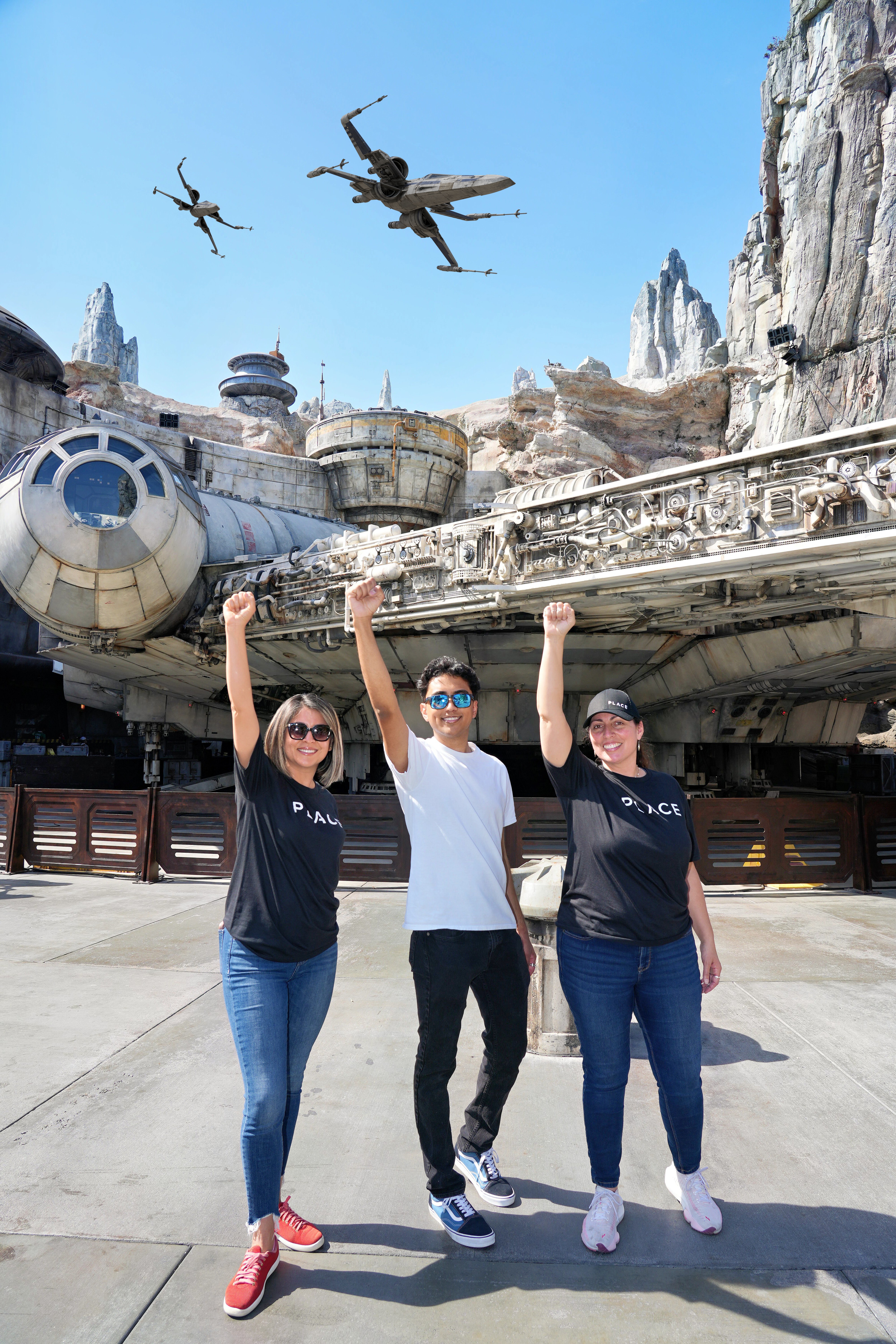 Three friends celebrating in front of the Millennium Falcon at Disneyland's Star Wars: Galaxy's Edge, capturing the joy of a Southern California family day trip and creating lasting memories together.