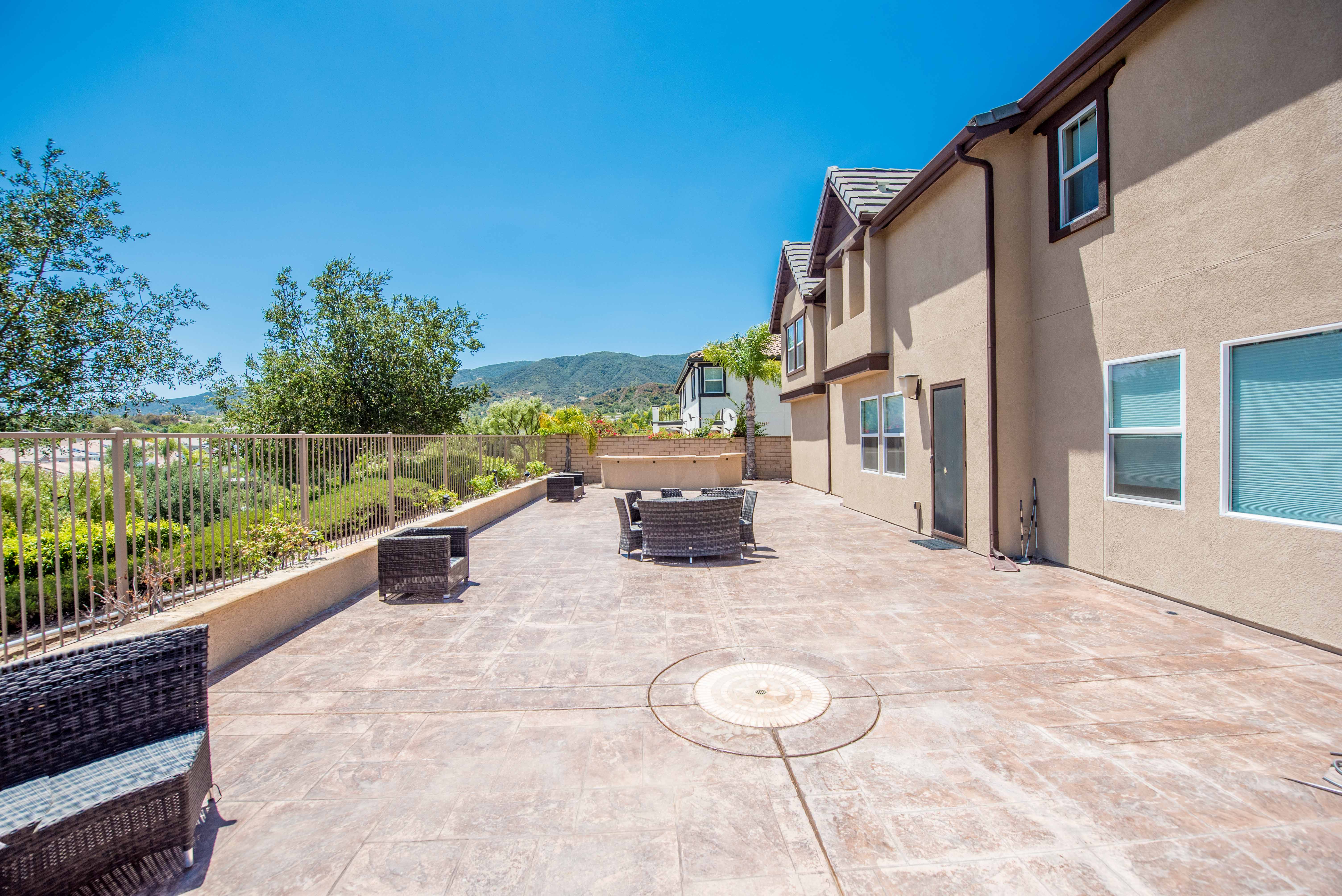 Expansive backyard patio at 3209 Stoneberry Lane in Corona featuring multiple outdoor seating areas, mountain views, and private outdoor living space designed for entertaining and relaxation.
