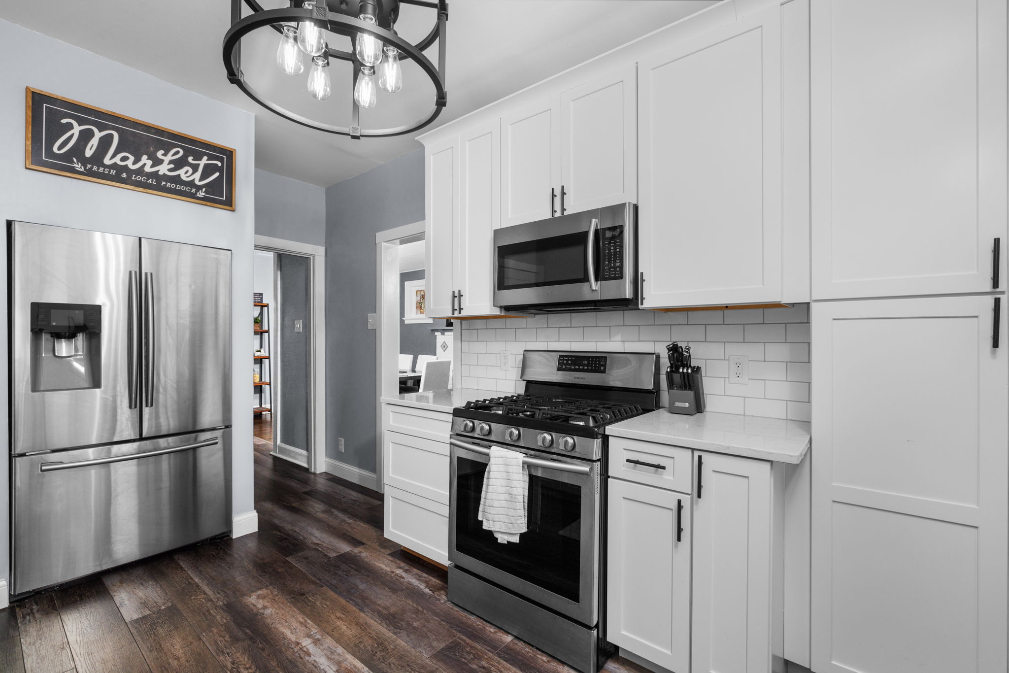 A white kitchen with stainless steel appliances and a towel over the oven handle