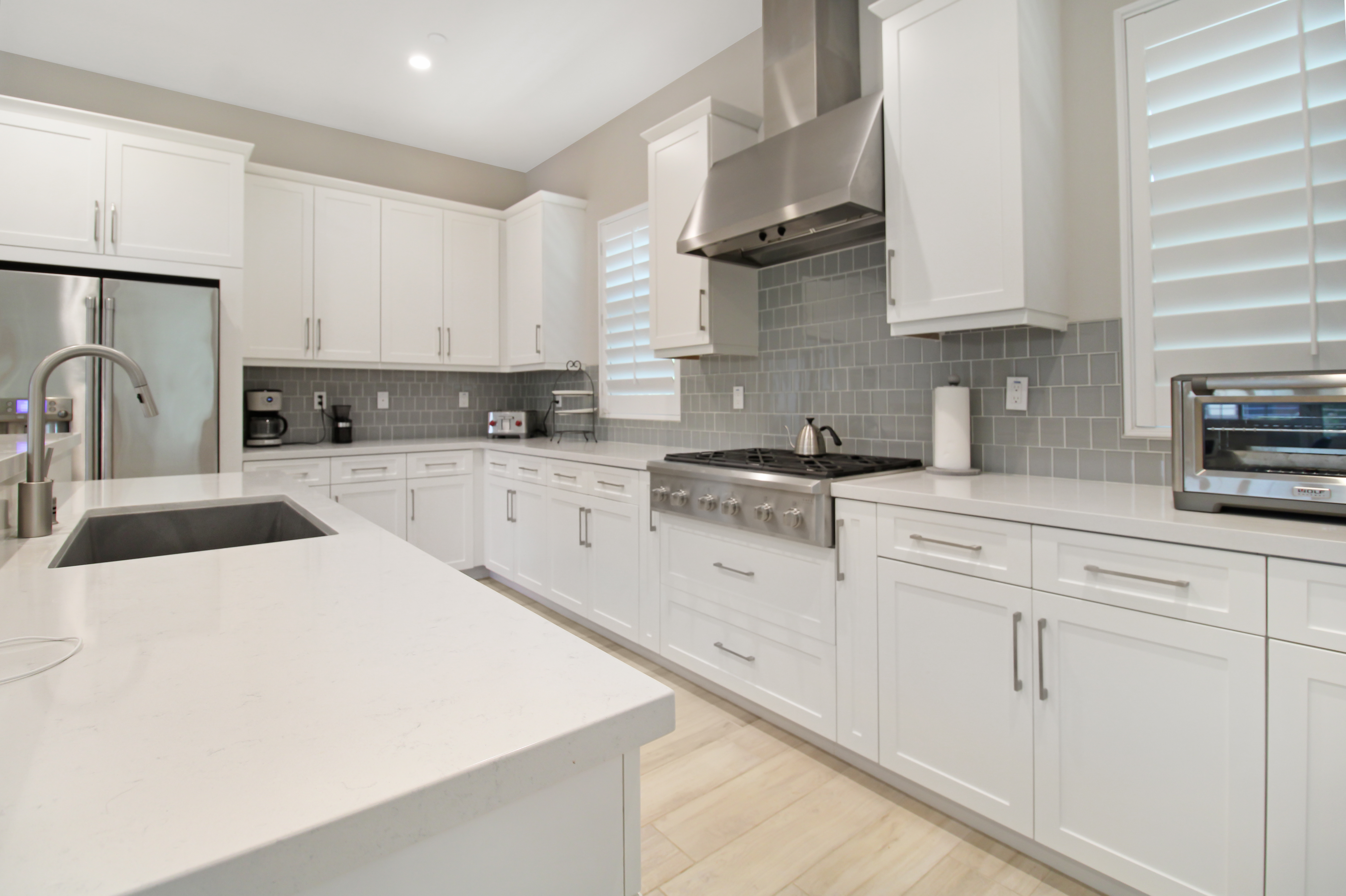 Kitchen with quartz waterfall island, Cafe by GE appliances, and white shaker cabinetry