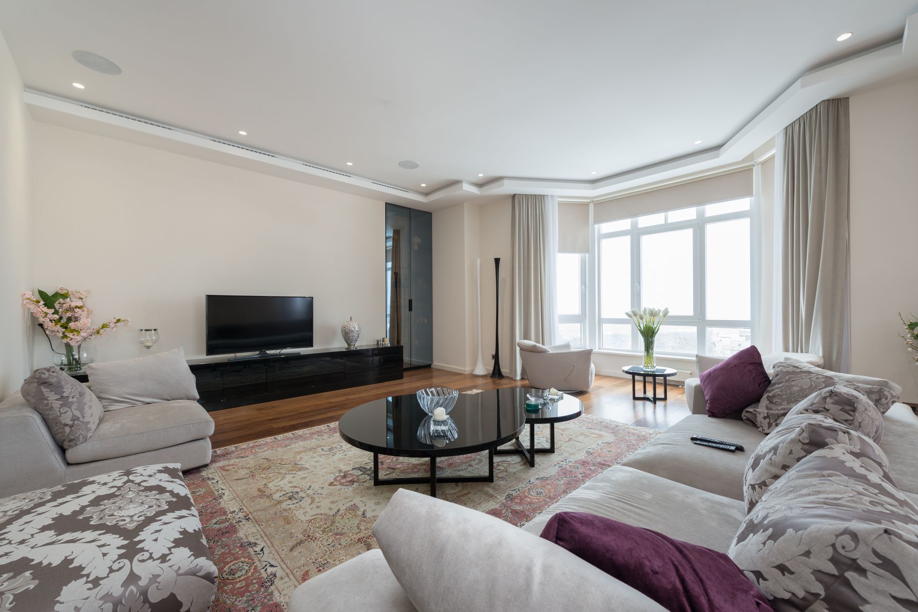 Bright staged living room with neutral sofas and large windows, the kind of space buyers explore on virtual home tours in New Hampshire