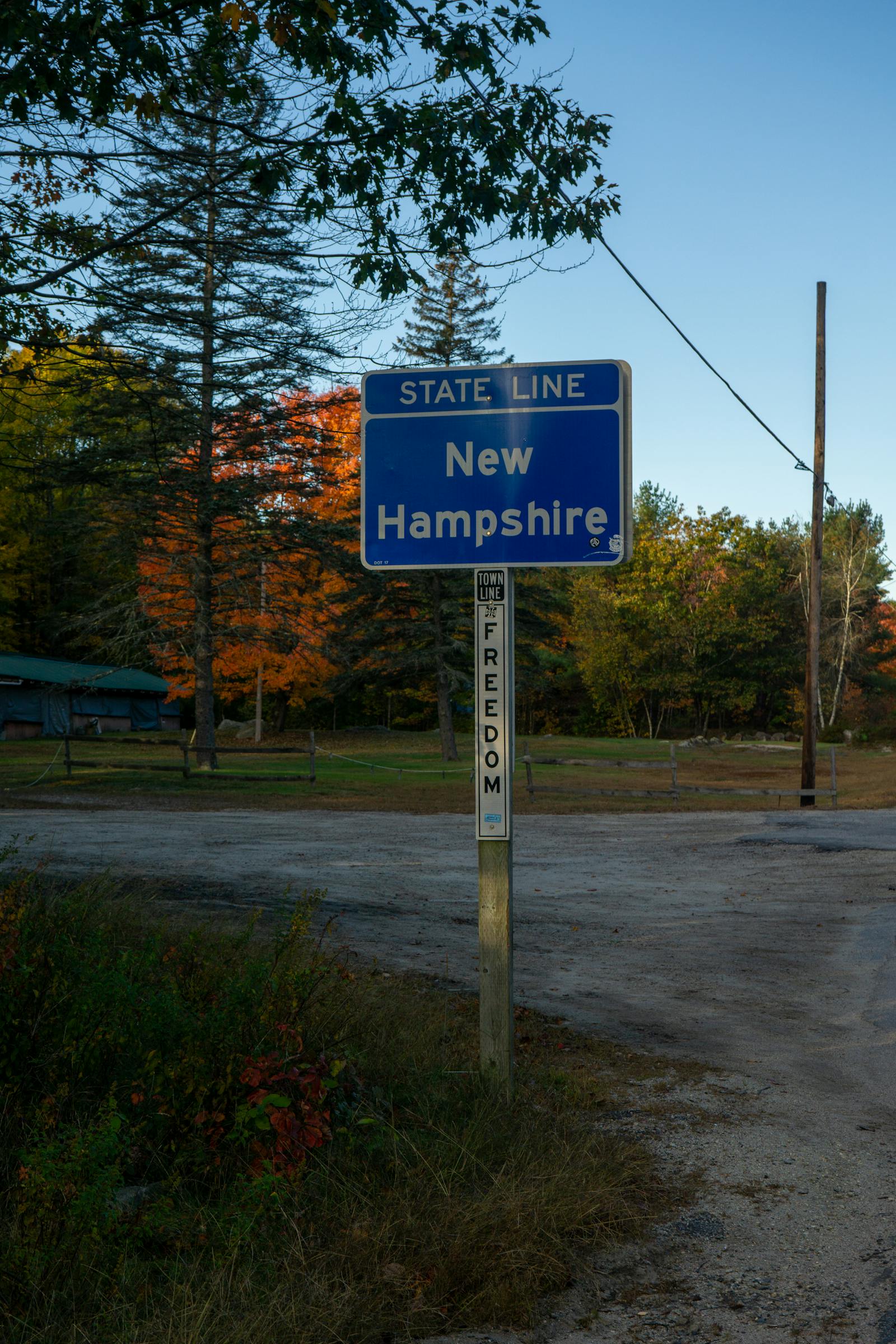 Welcome to New Hampshire state line sign with autumn foliage — relocating from Massachusetts to NH