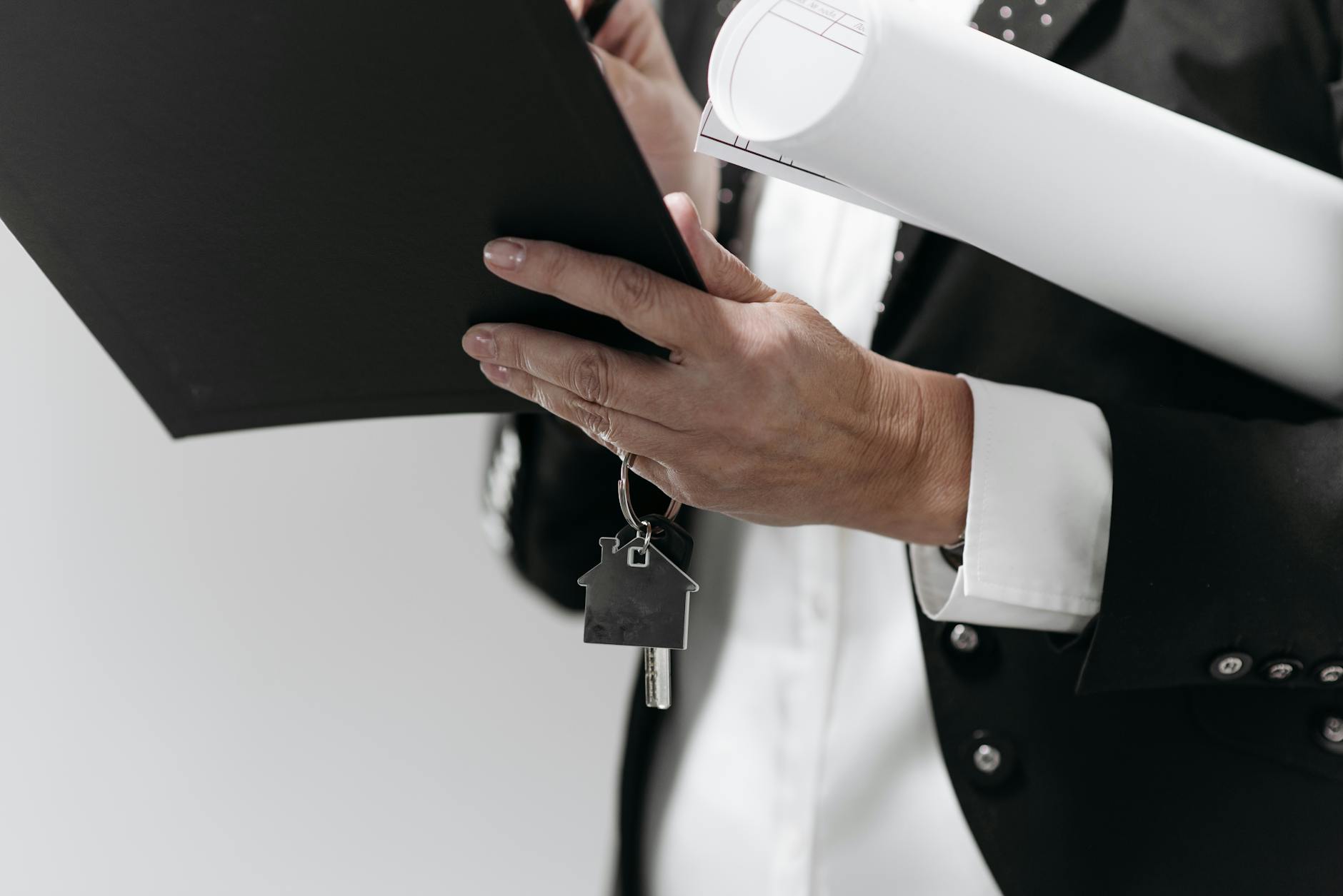 Real estate professional holding a contract folder, rolled documents, and a house-shaped keychain with key - preparing an earnest money deposit for a New Hampshire home offer