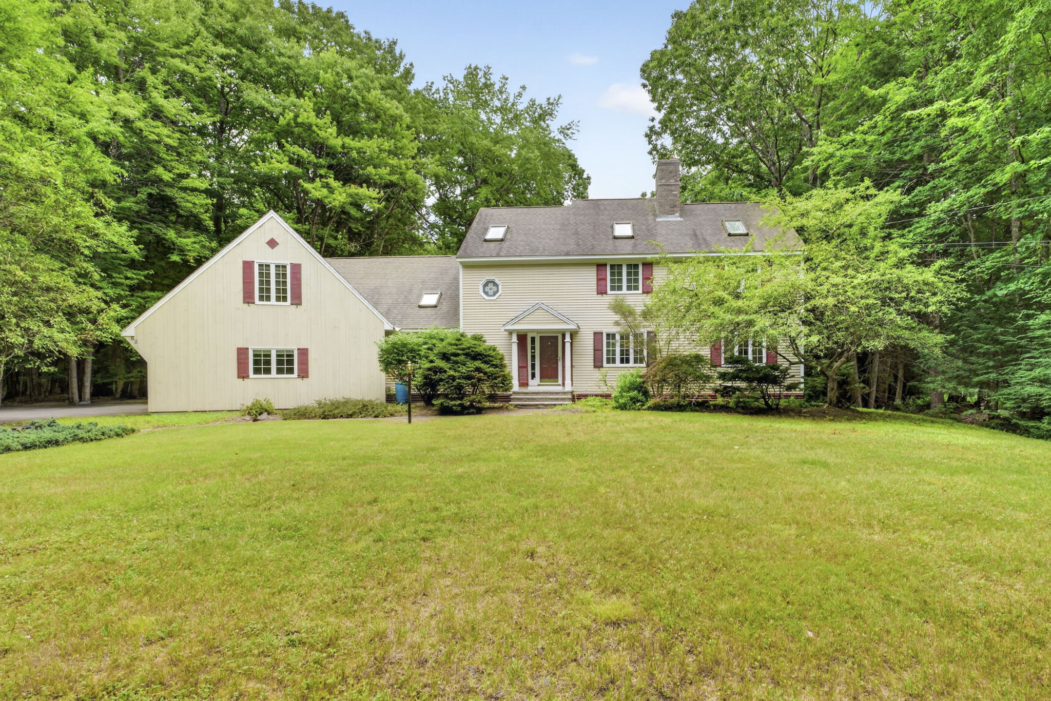 Summer view of a classic New England colonial home in Bedford NH — is it a good time to buy a house in New Hampshire