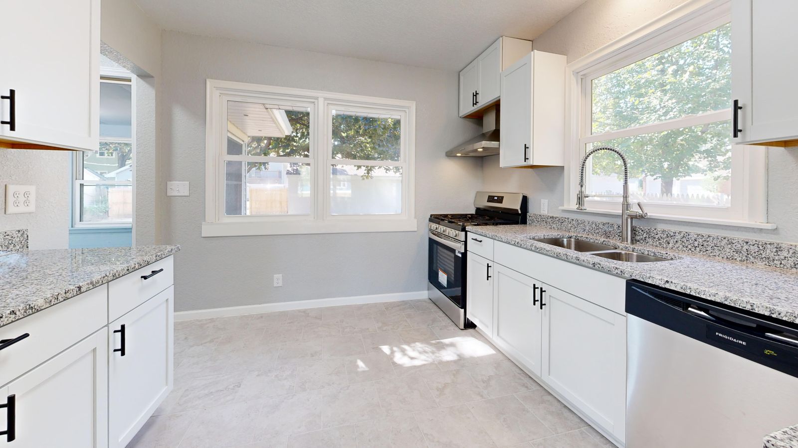 Bright white kitchen with granite countertops and stainless appliances in a home prepared for sale — cost to sell a house in New Hampshire