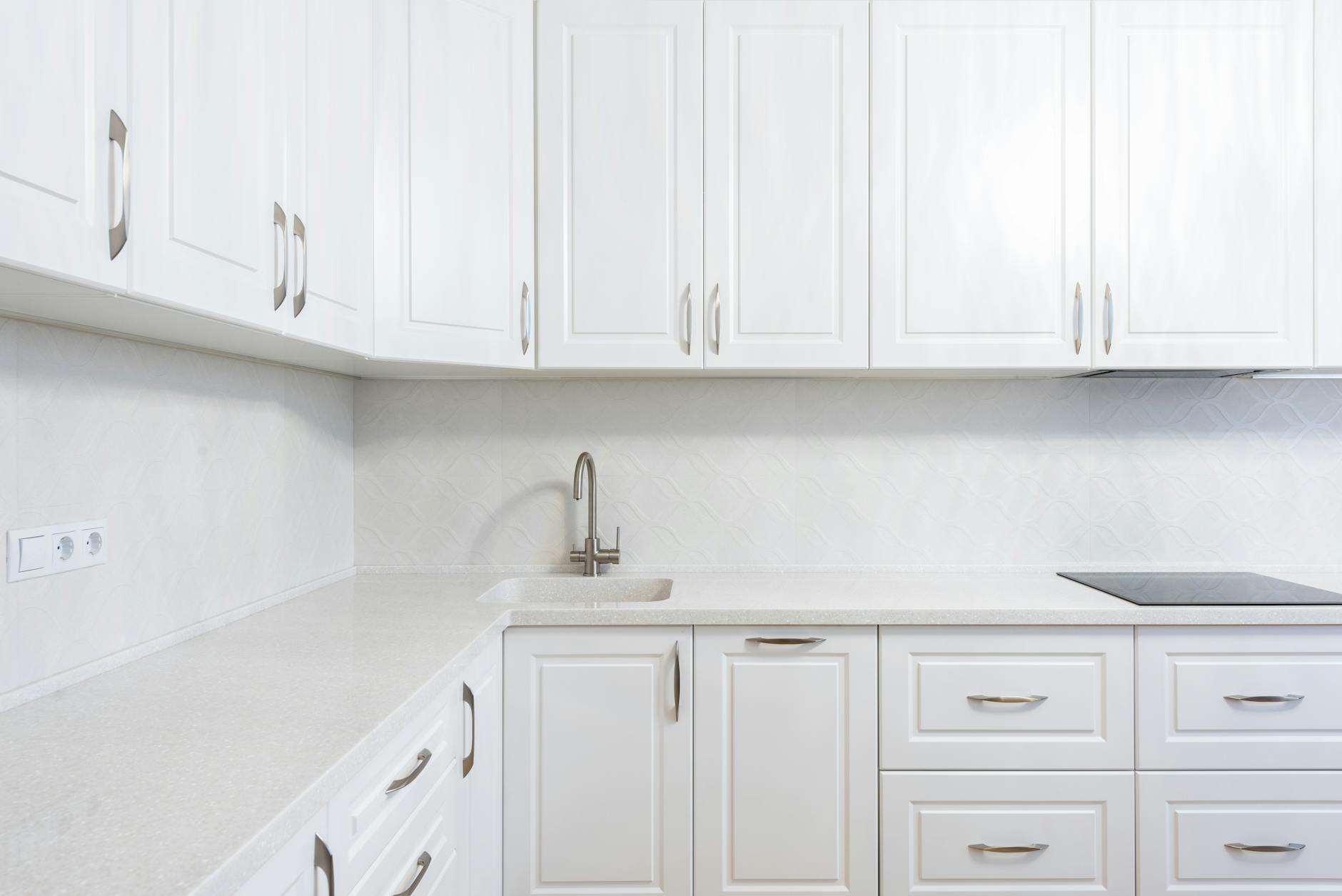 Bright, well-lit white kitchen with quartz counters and glossy cabinets — the kind of real estate photography that sells New Hampshire homes