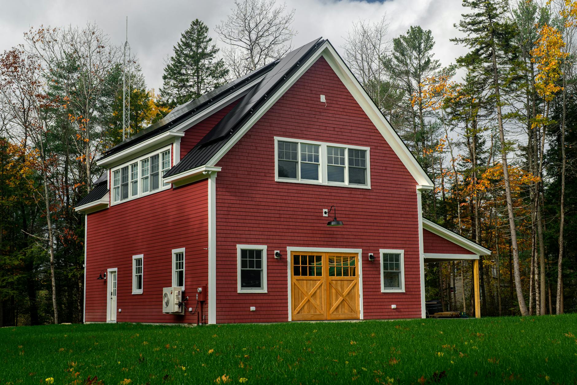 Red barn-style New England carriage house with a garage door and finished living space above — an example of a Nashua NH ADU