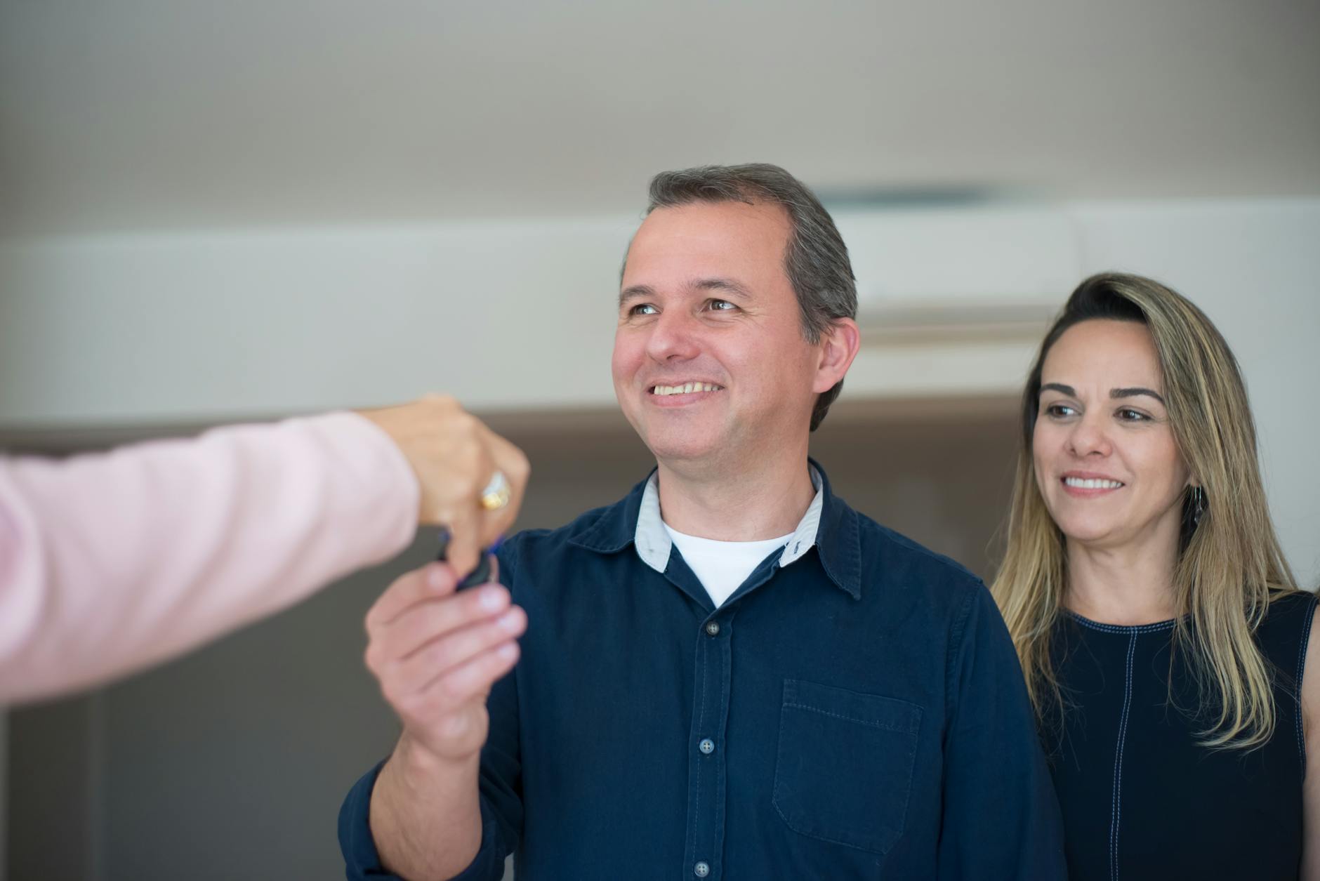 Smiling couple receiving house keys from a real estate agent - buying a home in New Hampshire