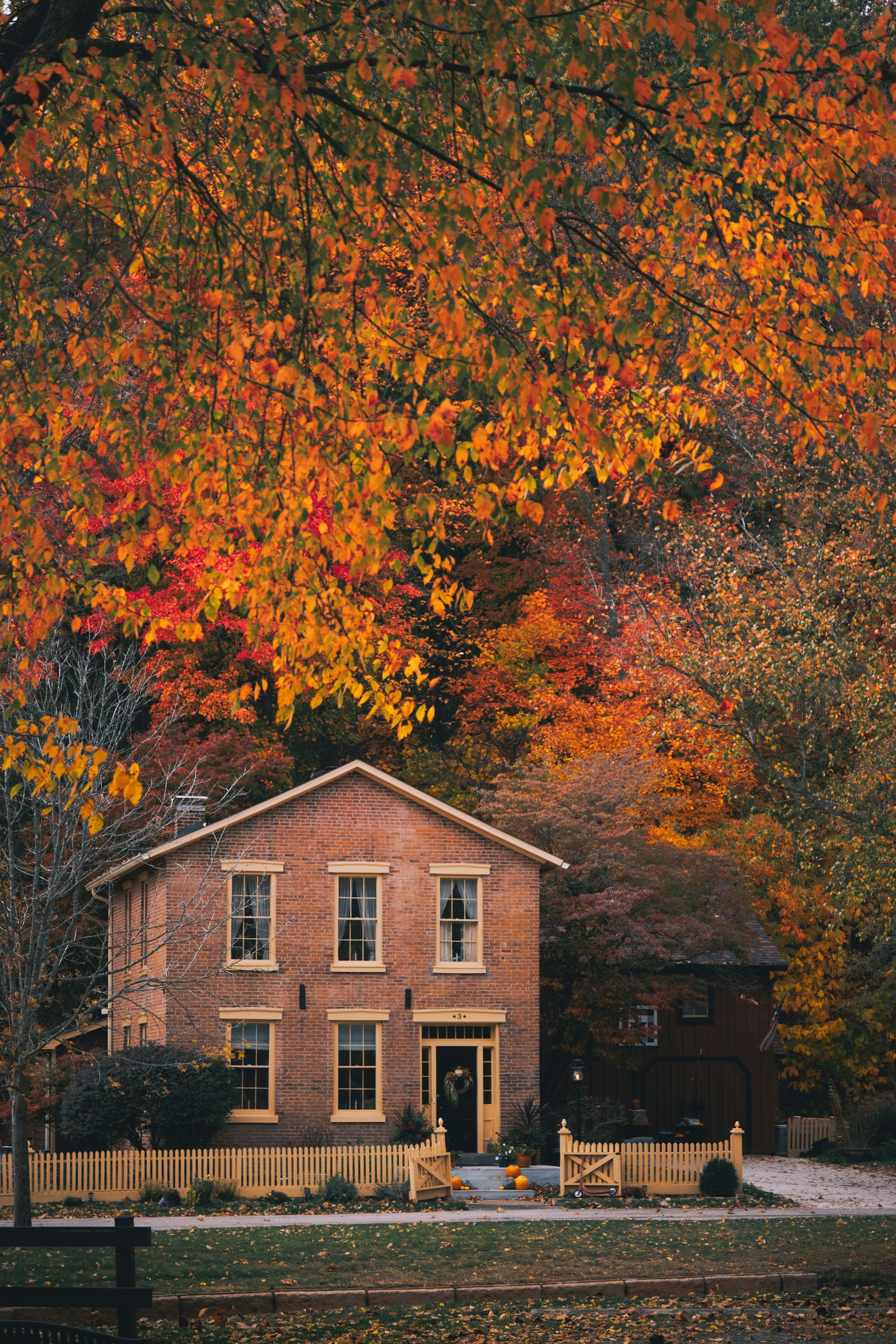 Brick colonial home in autumn surrounded by trees — Londonderry NH real estate