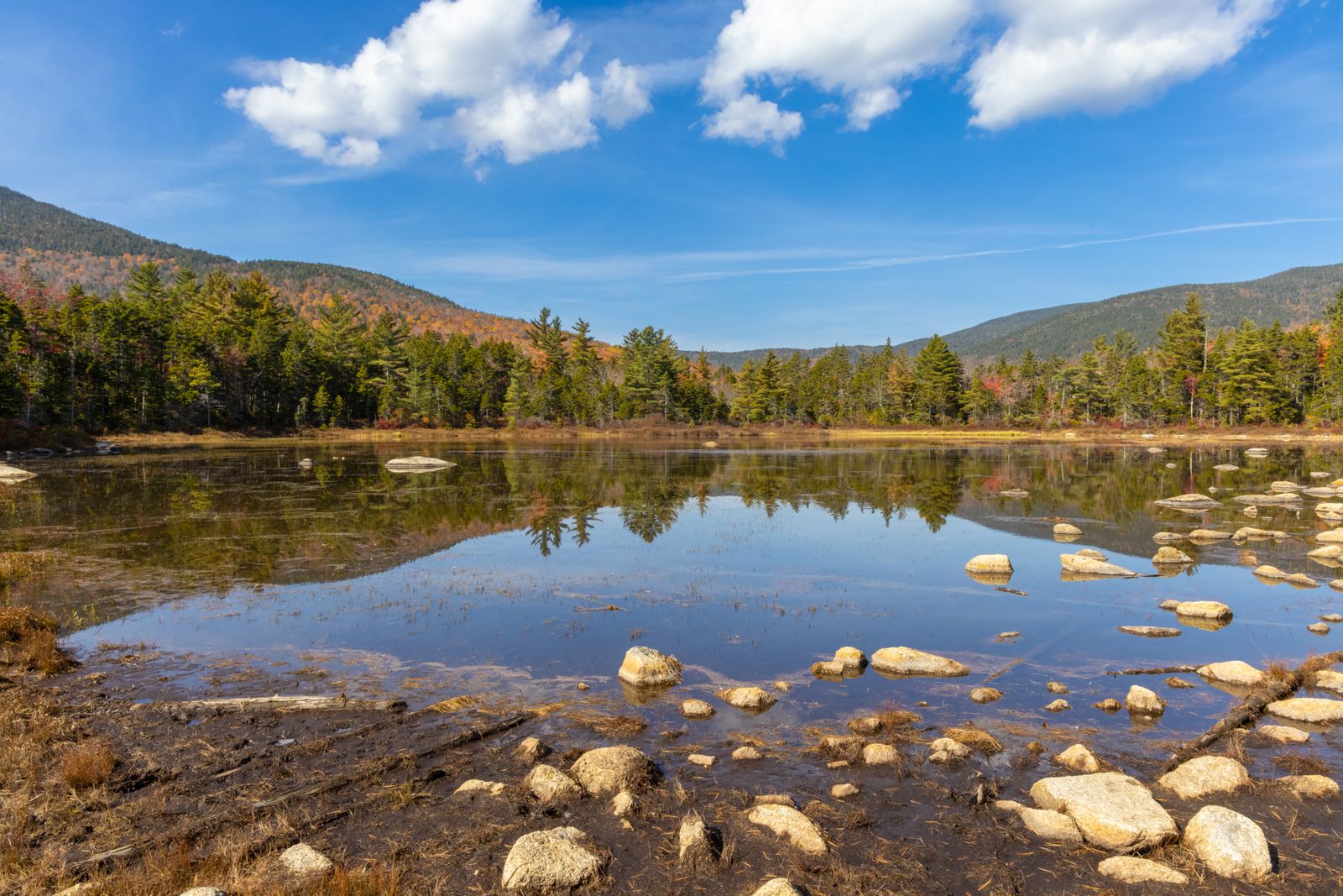 Early-fall foliage and evergreens reflected in a rocky White Mountains pond in New Hampshire - Concord vs Manchester NH comparison