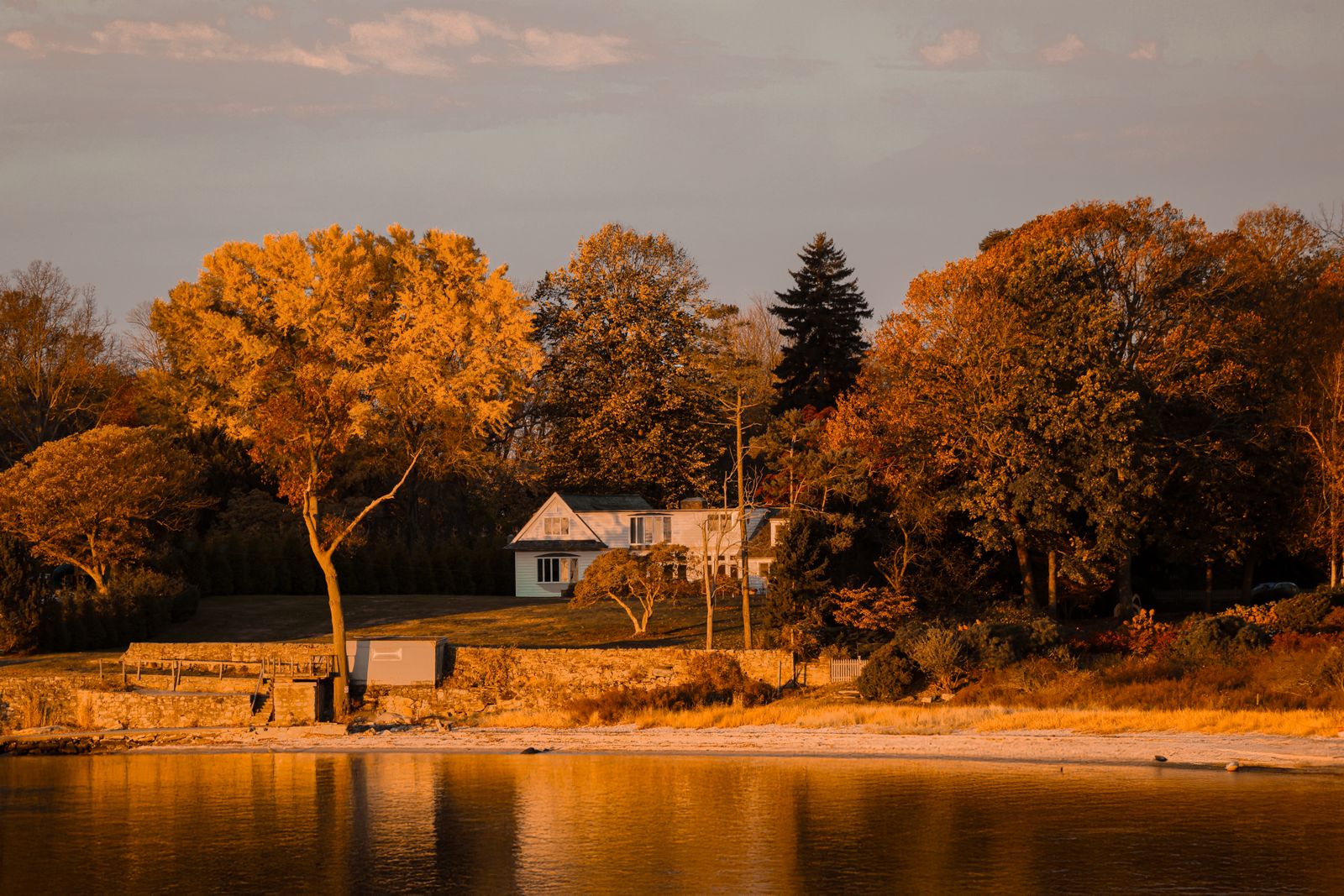 White New England colonial home at autumn sunset across the water - selling a house before buying in New Hampshire
